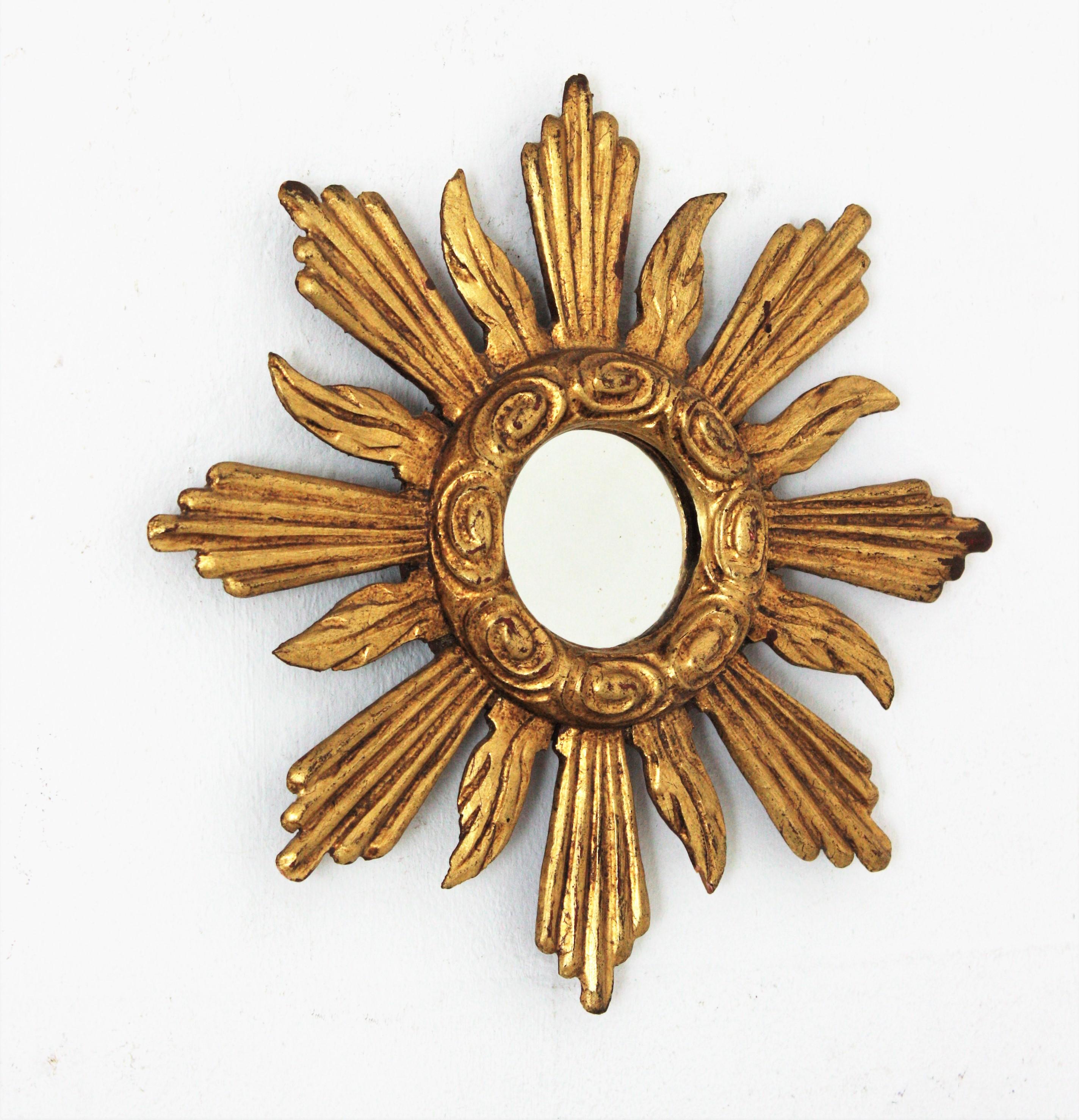 Mini sized sunburst mirror, carved wood, gold leaf. Spain, 1940s
Eye-catching finely carved sunburst mirror with rays in two sizes and geometric and striped decorations.
Nice aged patina and original gold leaf gilding.
This lovely mini sunburst