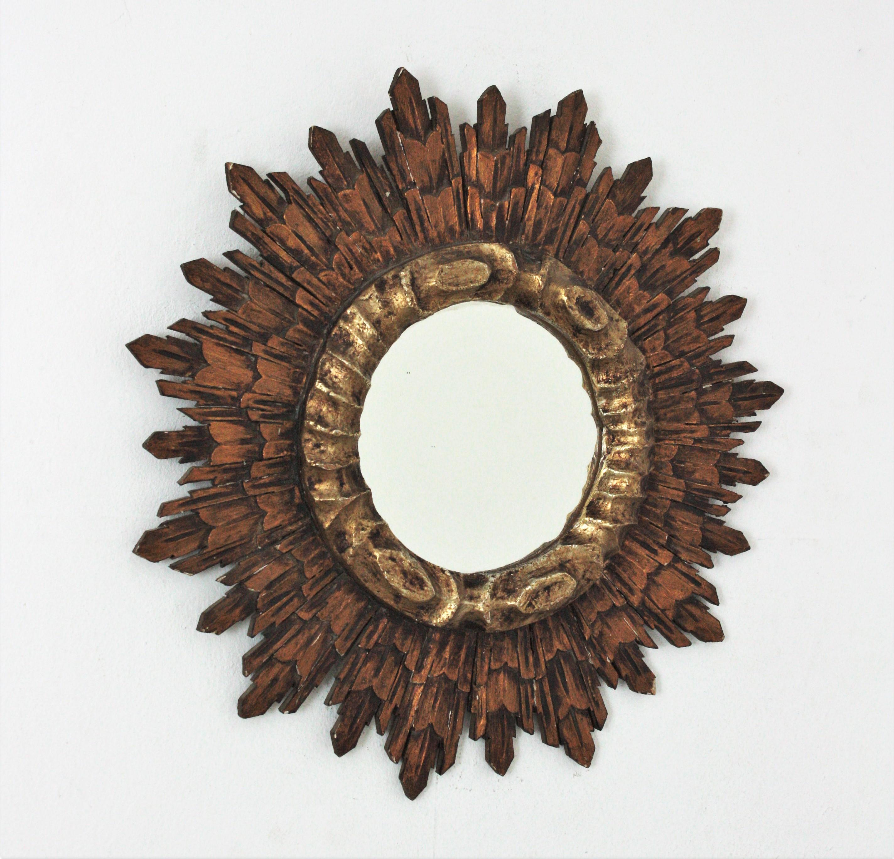 Outstanding Baroque style silver and gold leaf giltwood carved sunburst mirror, Spain, 1930s-1940s.
The carved wood frame is finished with gesso and gold leaf gilding in bronze tone. The central patterned frame surrounding the round glass is