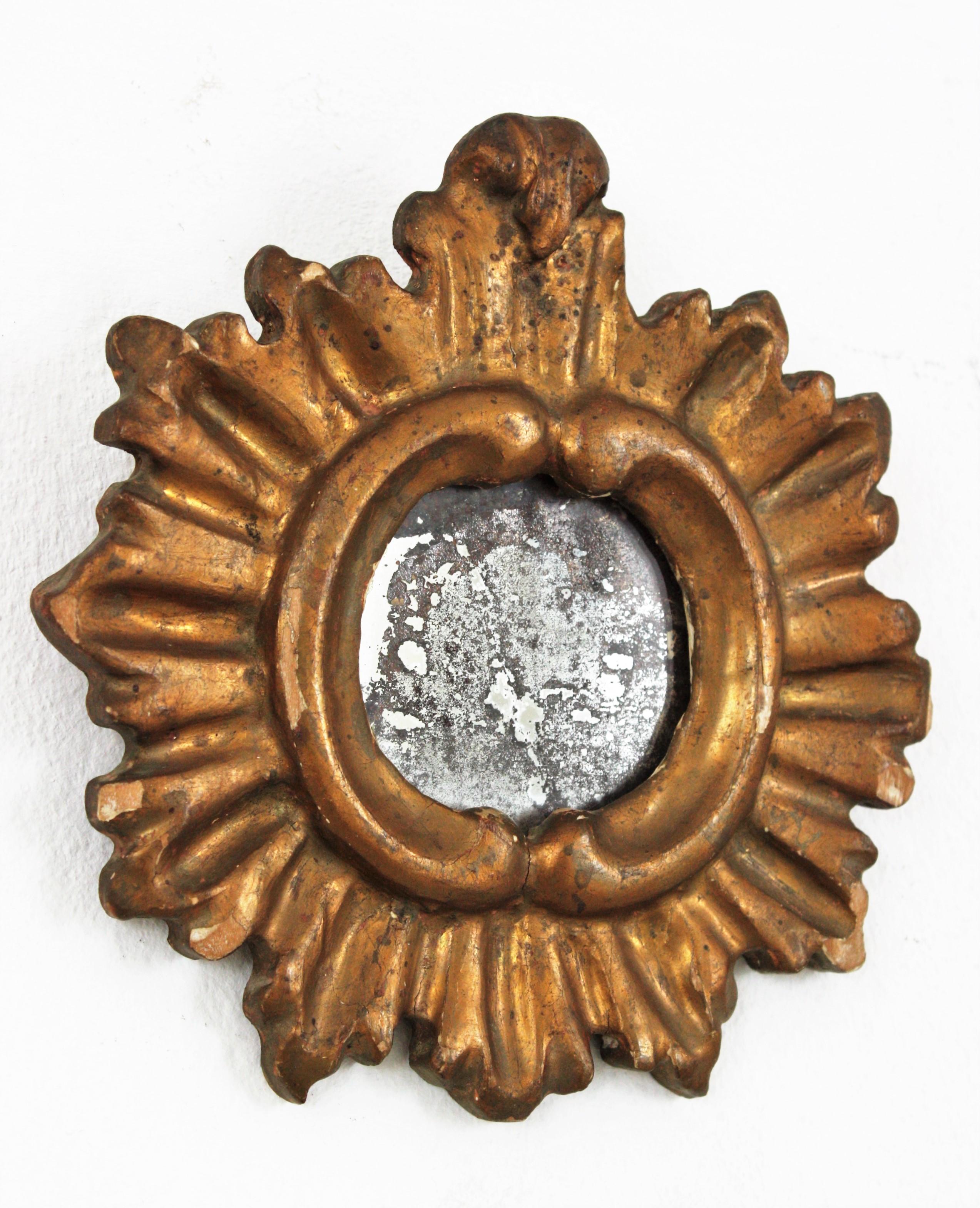 Antique Spanish Baroque carved giltwood sunburst mirror with crest. Spain, 19th century.
This lovely collection mirror has a carved frame covered with gesso and gold leaf finishing. It has a terrific aged patina and the original antique