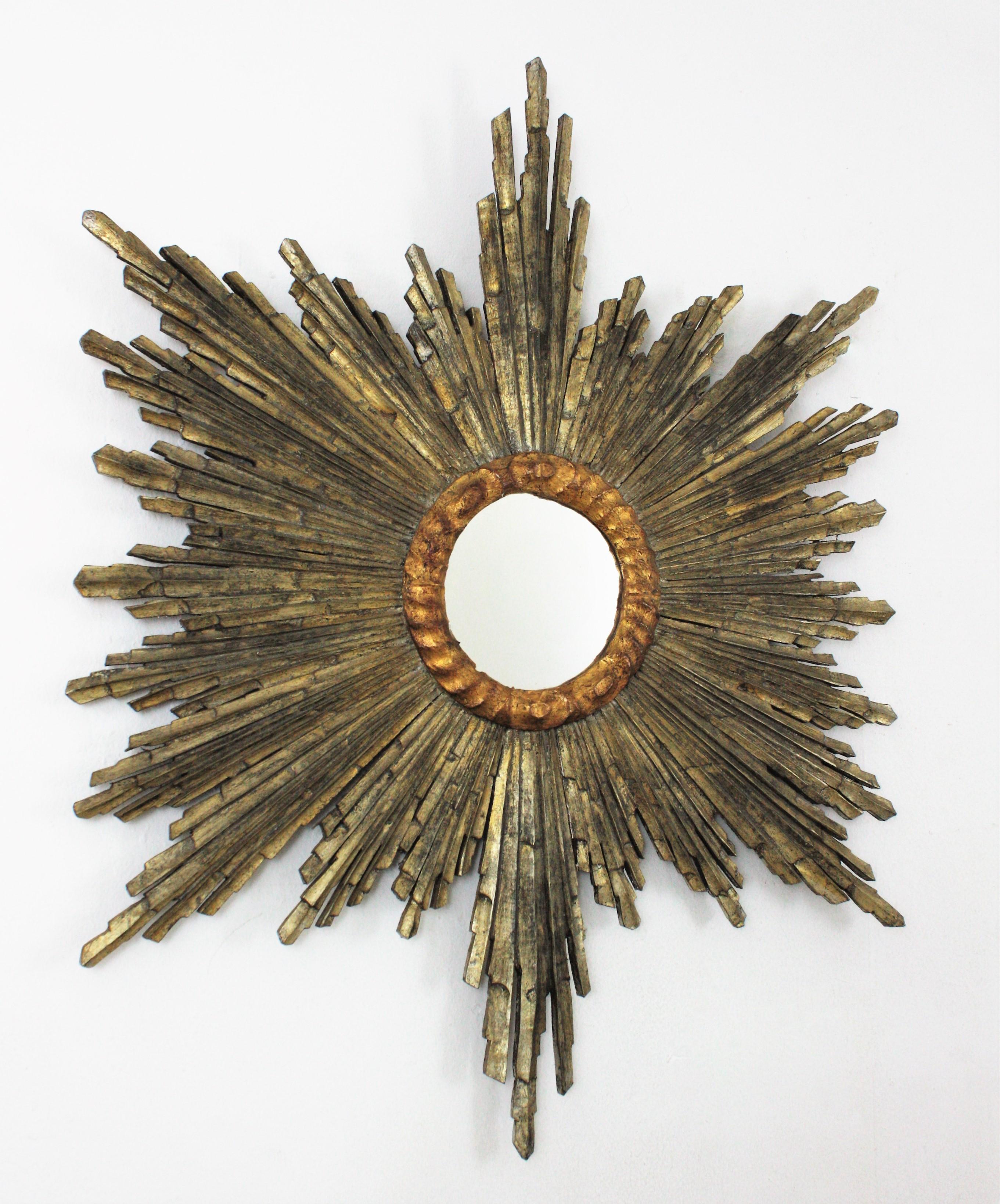 Outstanding Baroque style silver and gold leaf giltwood sunburst mirror, Spain, 1930s-1940s.
This gold and silver gilt carved wood sunburst mirror has a terrific aged patina showing its original gilding in two tones and wearing its antique