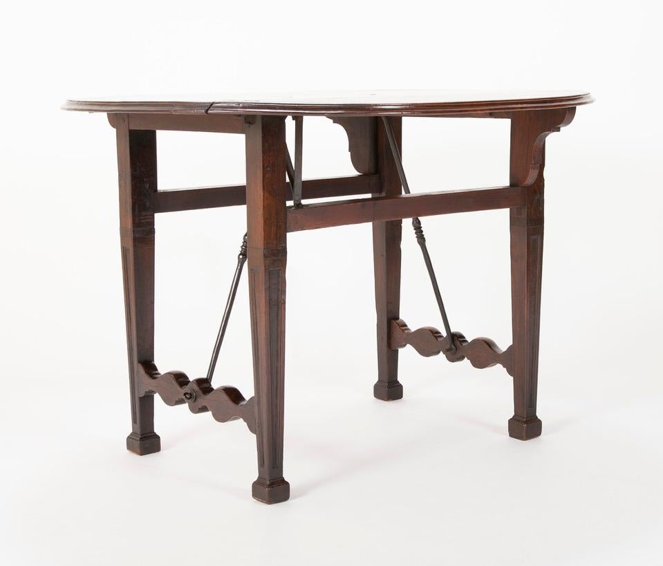18th century Spanish Baroque walnut table with drop leaves and wrought iron stretchers. Rare and unusual, possibly unique form, with straight legs and beautiful s-form stretchers to which the iron supports are attached. A nice detail is the hinges