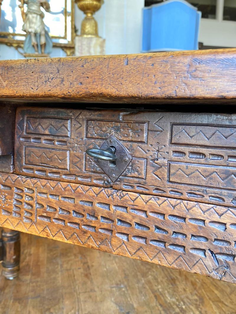 Rectangular single plank top over three incised carved drawers raised on baluster legs joined by stretchers. similar carved on the opposite side.