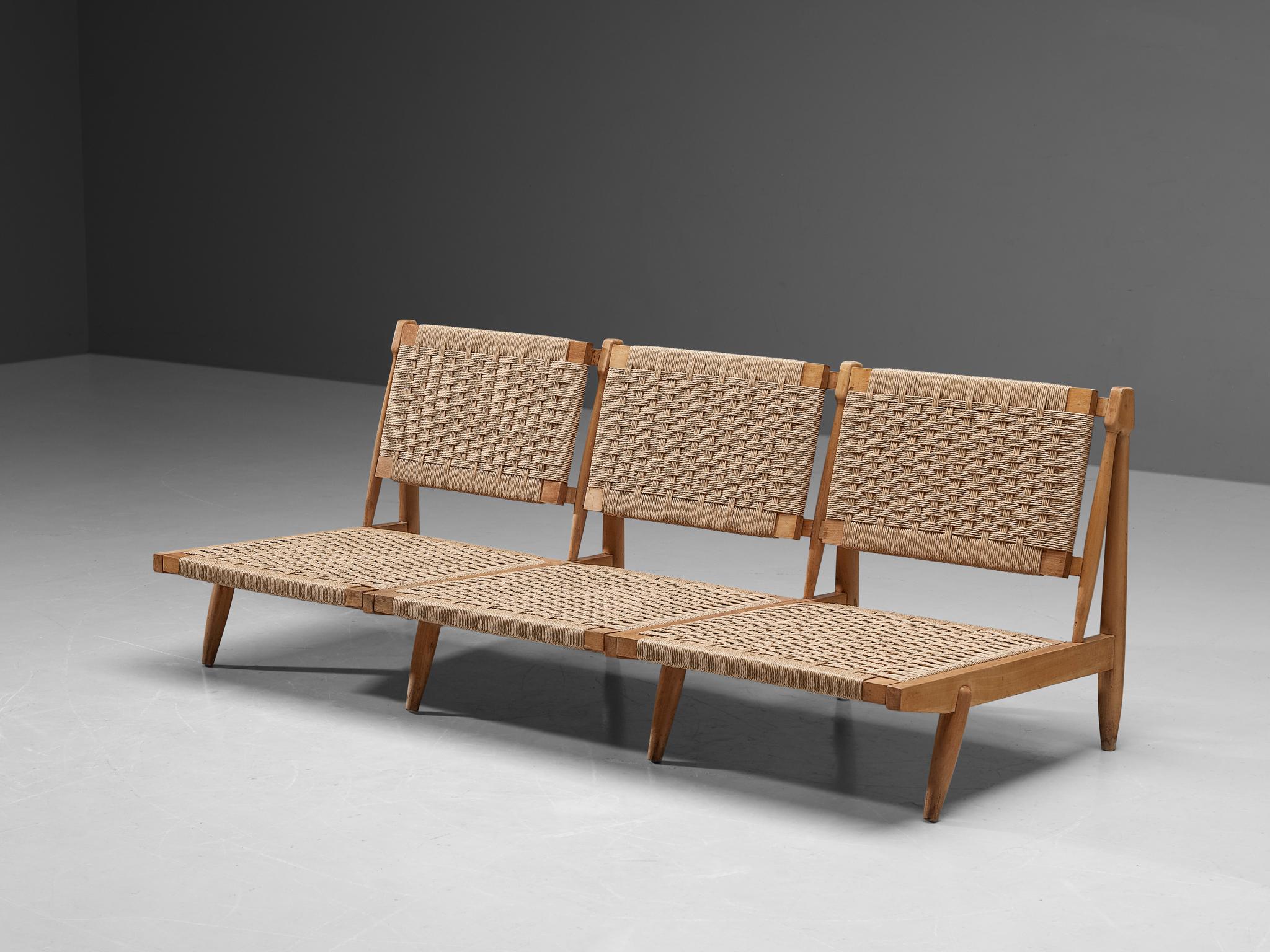 Bench or sofa, straw, beech, Spain, 1960s. 

This sofa or bench is designed with a woven straw backrest and seat that is in good condition. The front legs of the sofa are pointed outwards and feature interesting cylindrical lines. The beech frame