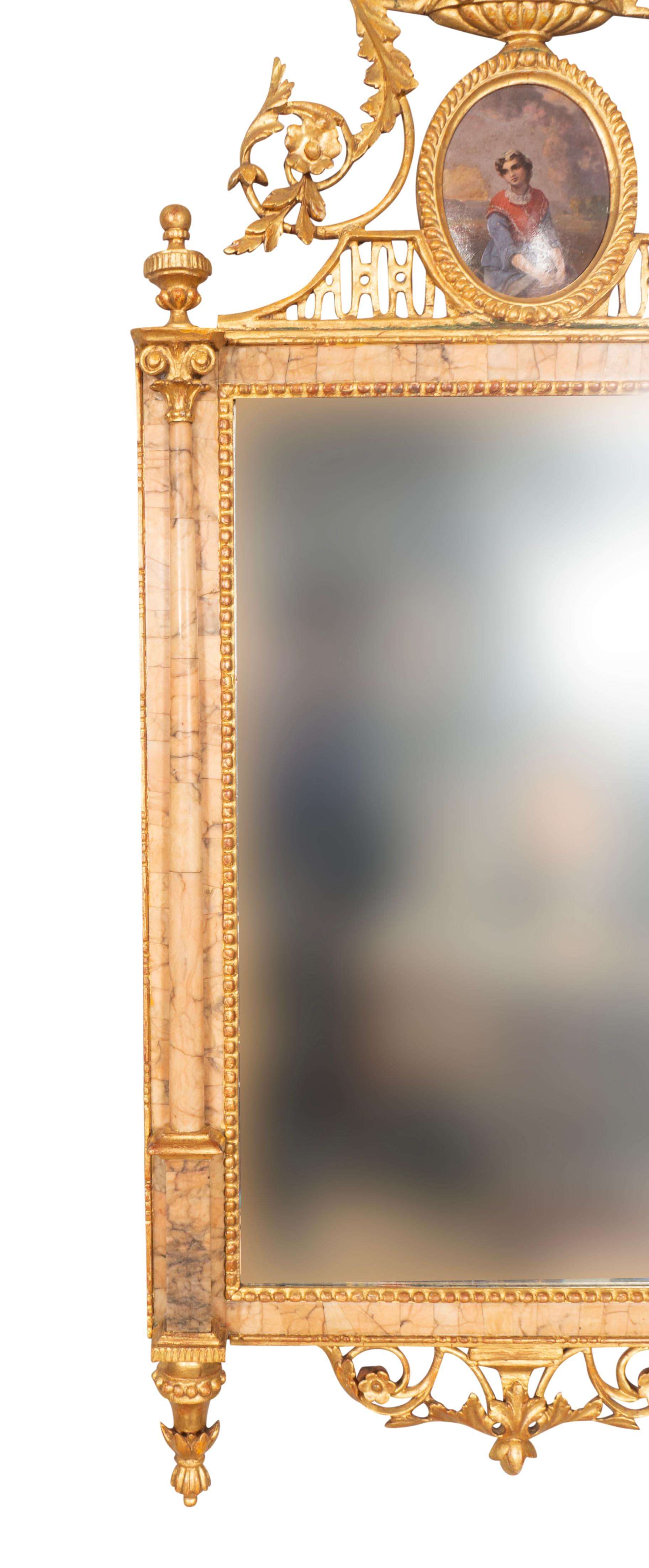 Avec une urne et un cimier de fleurs sur un portrait ovale. Miroir dans un cadre en marbre avec des détails en bois doré.