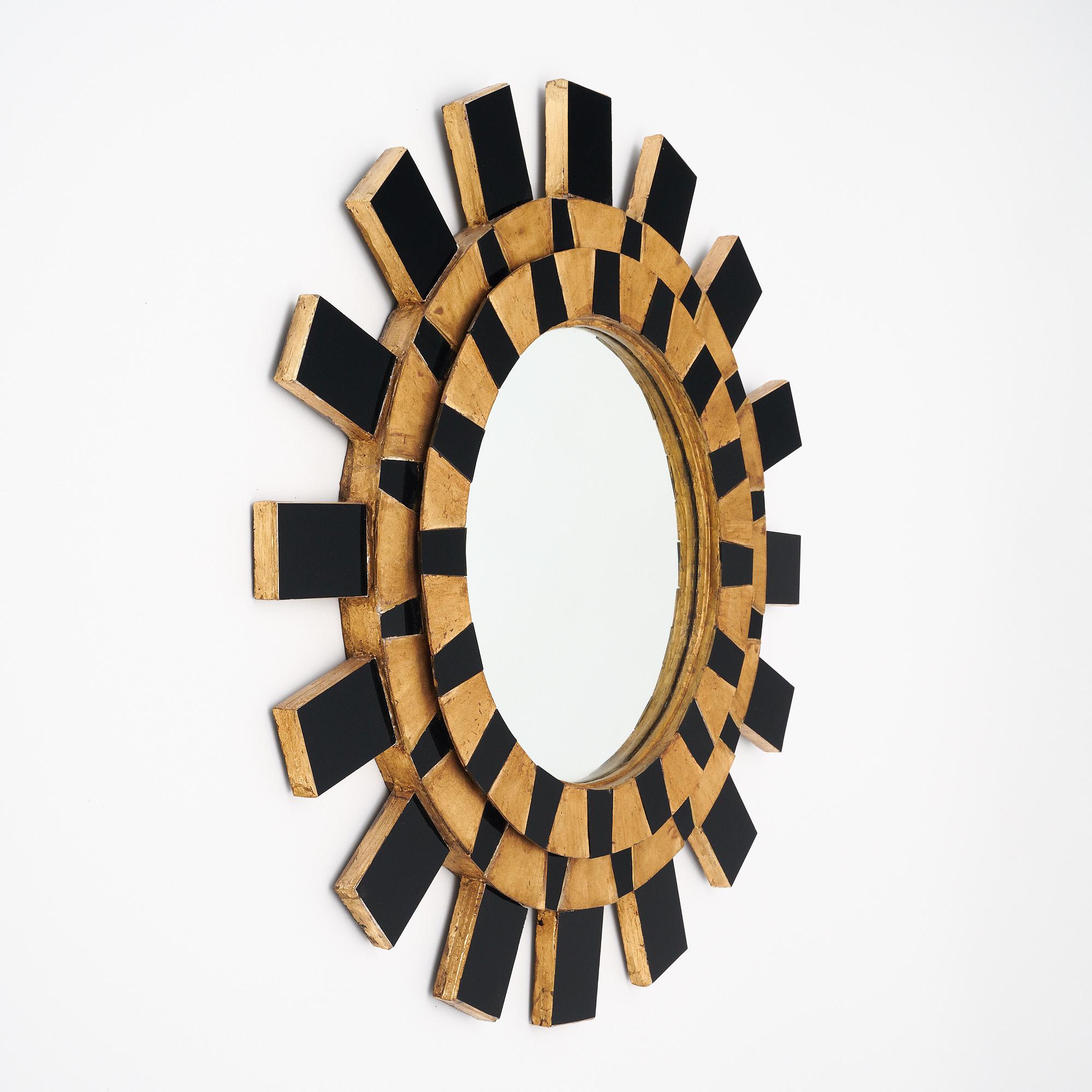 Miroir ensoleillé d'origine espagnole. Cette pièce comporte un miroir circulaire central. La structure est en bois avec des rayons émanant de verre noir et de feuilles d'or. L'ensemble du miroir a une structure en bois avec un placage en verre noir