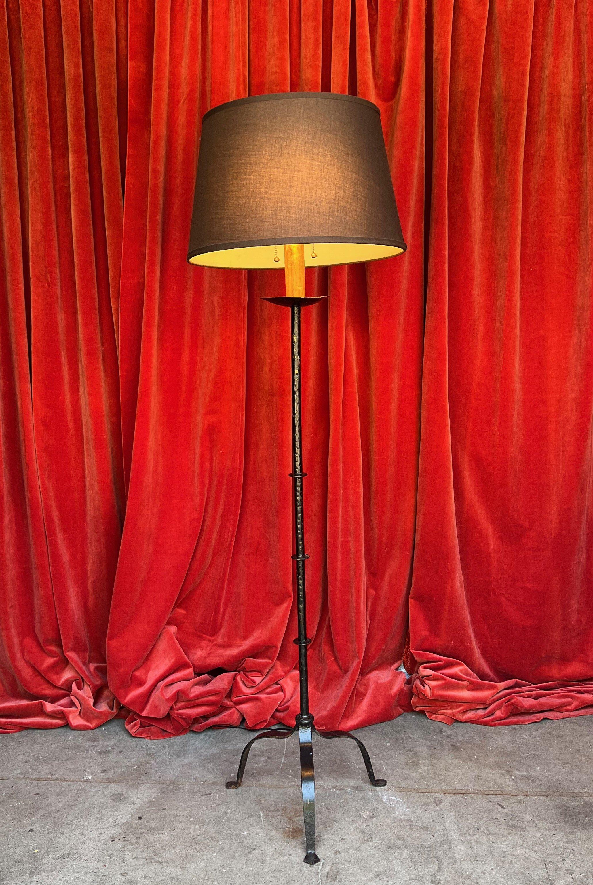 A sophisticated Spanish 1950s iron floor lamp, meticulously handcrafted and featuring a sleek black finish. Boasting exceptional quality and timeless allure, this lamp stands at an impressive 63 inches high with a 15½ inch base width. Its versatile