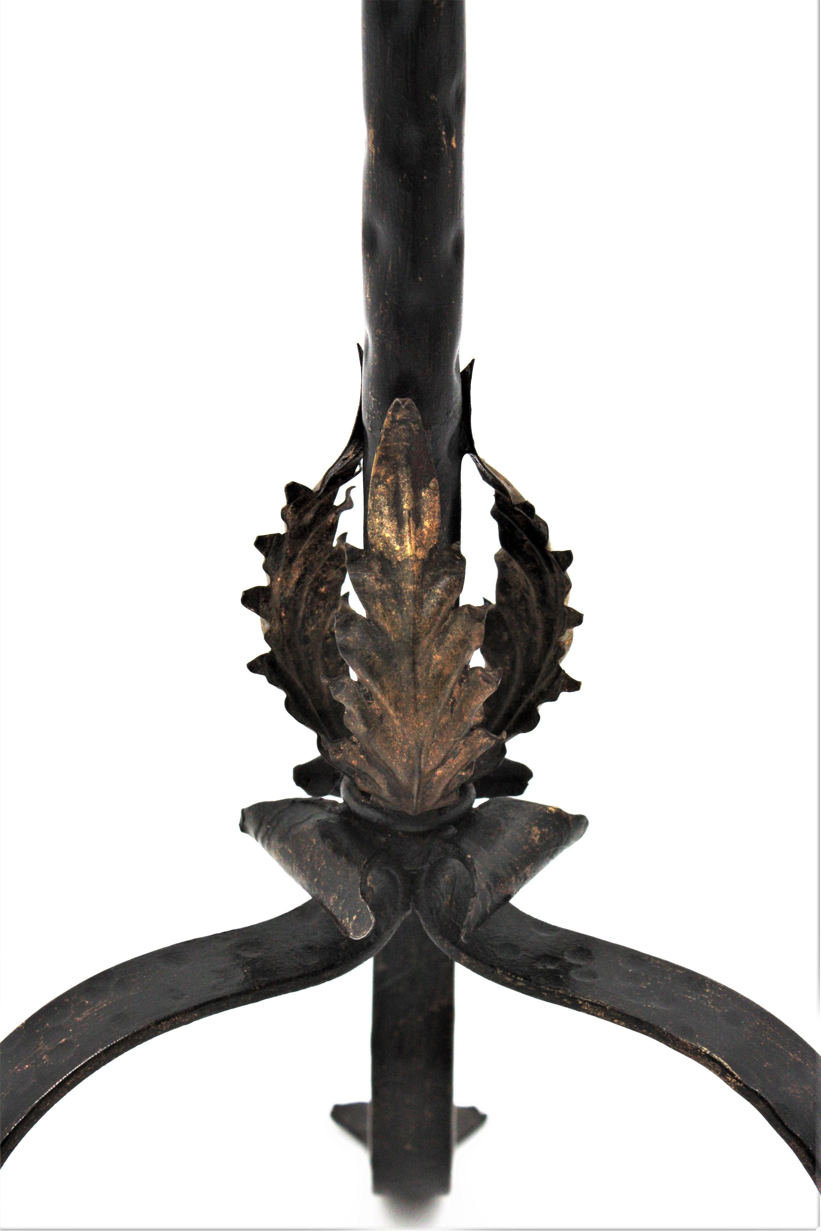 Spanish black painted hand-hammered iron gueridon, end table or cocktails table with gilt iron leaves decorations. Spain, 1940s.
This table was handcrafted in wrought iron and patinated in black with wax finishing. It has three gold gilt iron