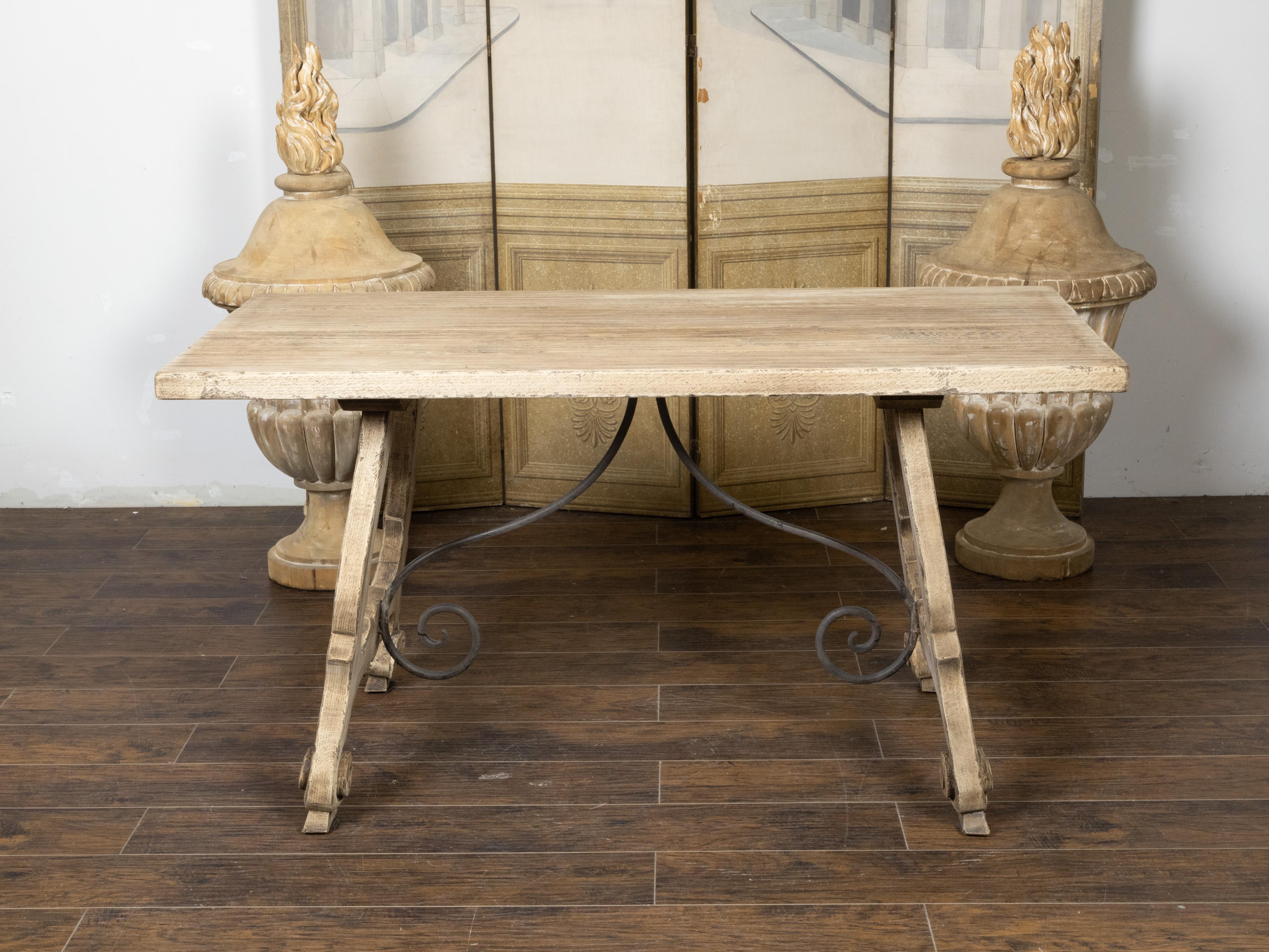 A Spanish bleached oak Fratino table from the 19th century, with Baroque style lyre shaped base, scrolling feet, iron stretchers and weathered appearance. Created in Spain during the 19th century, this Fratino table features a bleached oak finish