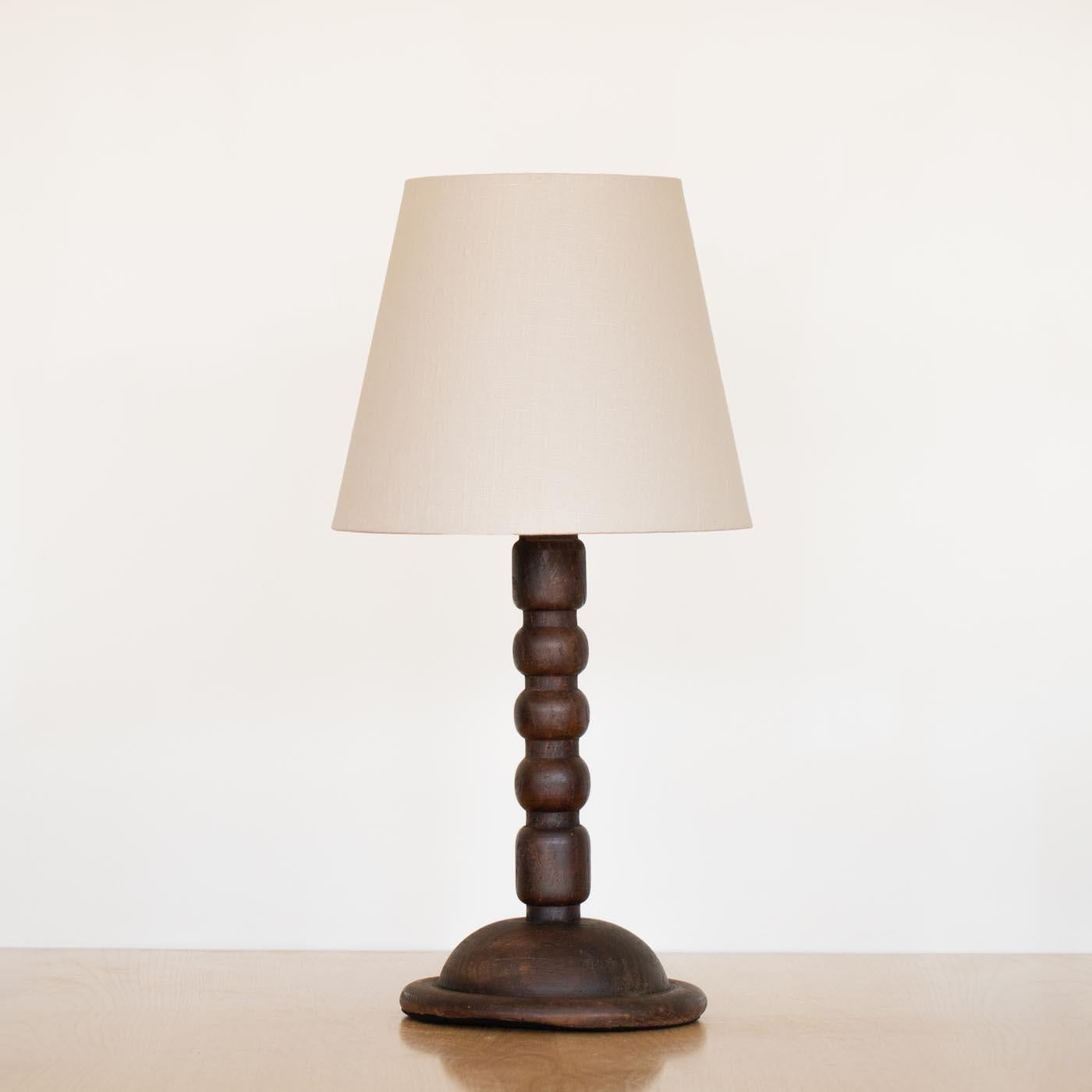 Magnifique lampe de table en bois vintage d'Espagne, années 1940. Épaisses rainures de canette en bois sculpté dans la tige. Finition d'origine en bois foncé présentant une belle patine d'ancienneté. Nouveaux abat-jour en lin crème et câblage refait