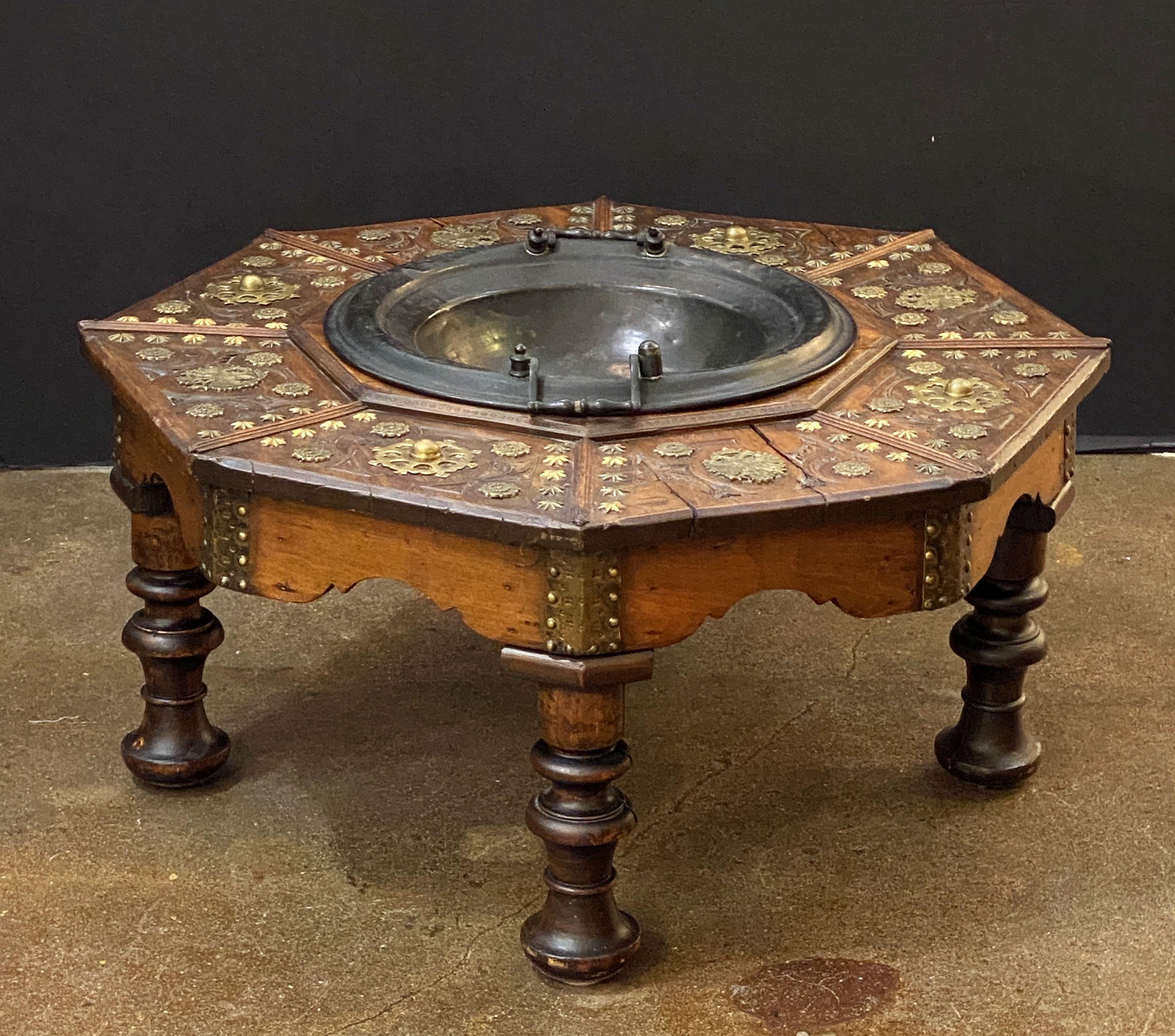 A fine Spanish carved walnut & brass warming or brazier table in the Baroque style, circa 1880, featuring an octagonal profile and decorated with a mixture of skirting at the bottom and brass nails with plant elements on the top. featuring the