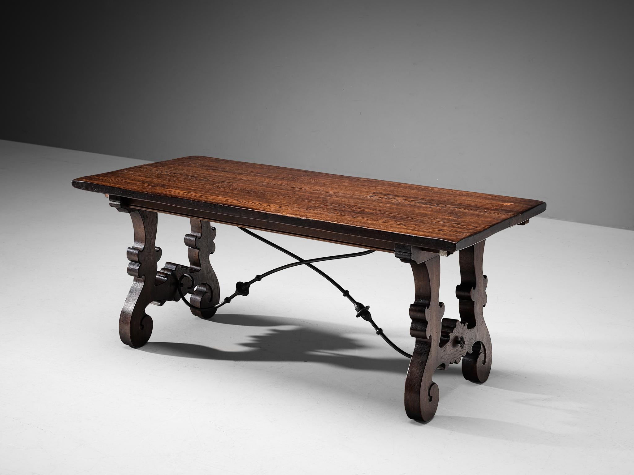 Dining table, stained oak, wrought iron, Spain, 1950s 

This exuberant dining table originates from Spain and shows the highly decorative characteristics of the 17th century Spanish baroque style. As is typical for baroque furniture design, their