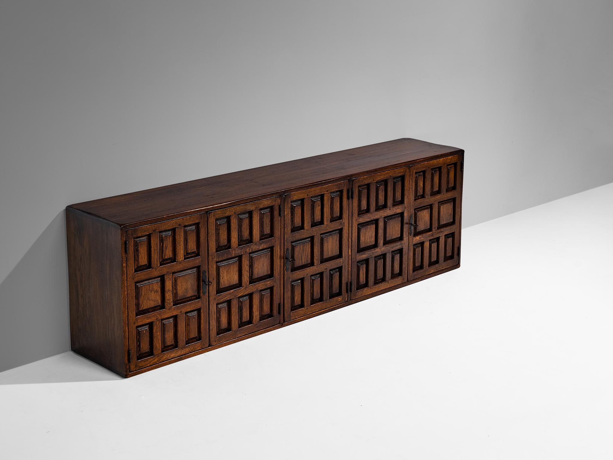 Buffet, frêne teinté, fer, Espagne, 1960

Ce meuble provient d'Espagne et présente les caractéristiques décoratives du design des meubles castillans du XVIe siècle. Les formes géométriques sculptées sur les panneaux de porte attirent immédiatement