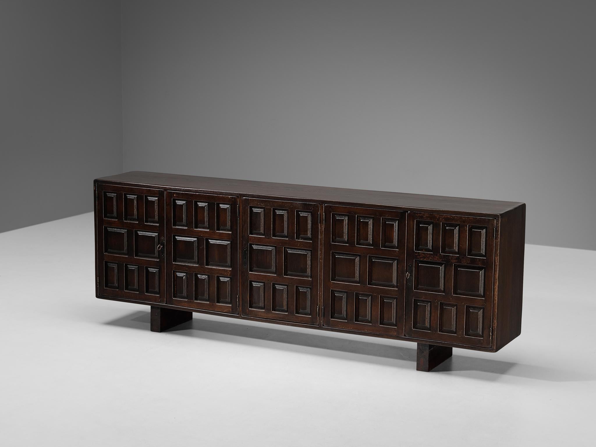 Sideboard, stained oak, iron, Spain, 1970s.

This cabinet originates from Spain and shows the decorative characteristics of the 16th century Castilian furniture design. The carved geometric shapes on the door panels immediately catch the eye and are