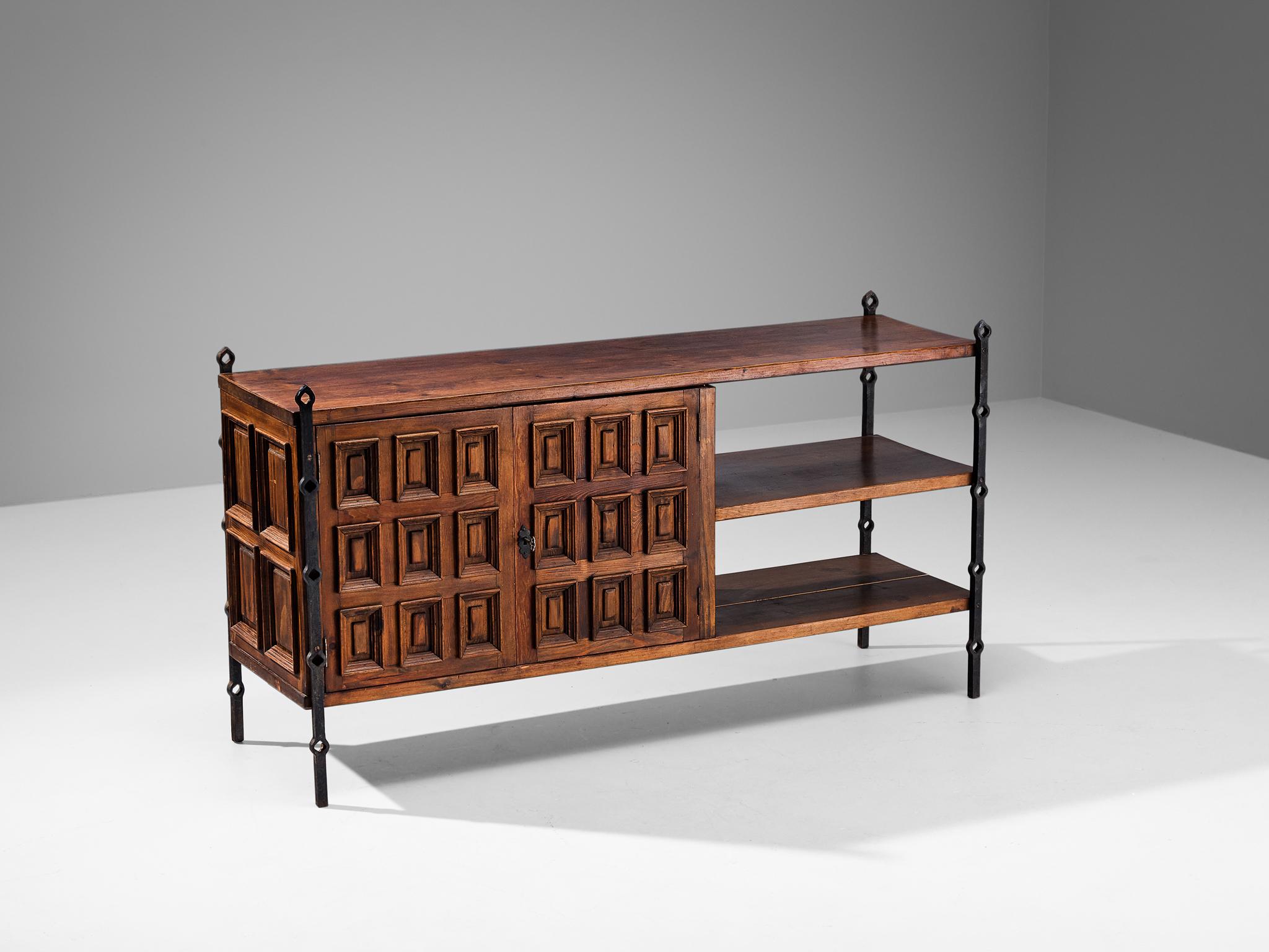 Sideboard, stained pine, iron, Spain, 1950s.

This cabinet originates from Spain and shows the decorative characteristics of the 16th century castilian furniture design. The corpus consists of a compartment with graphic designed door panels
