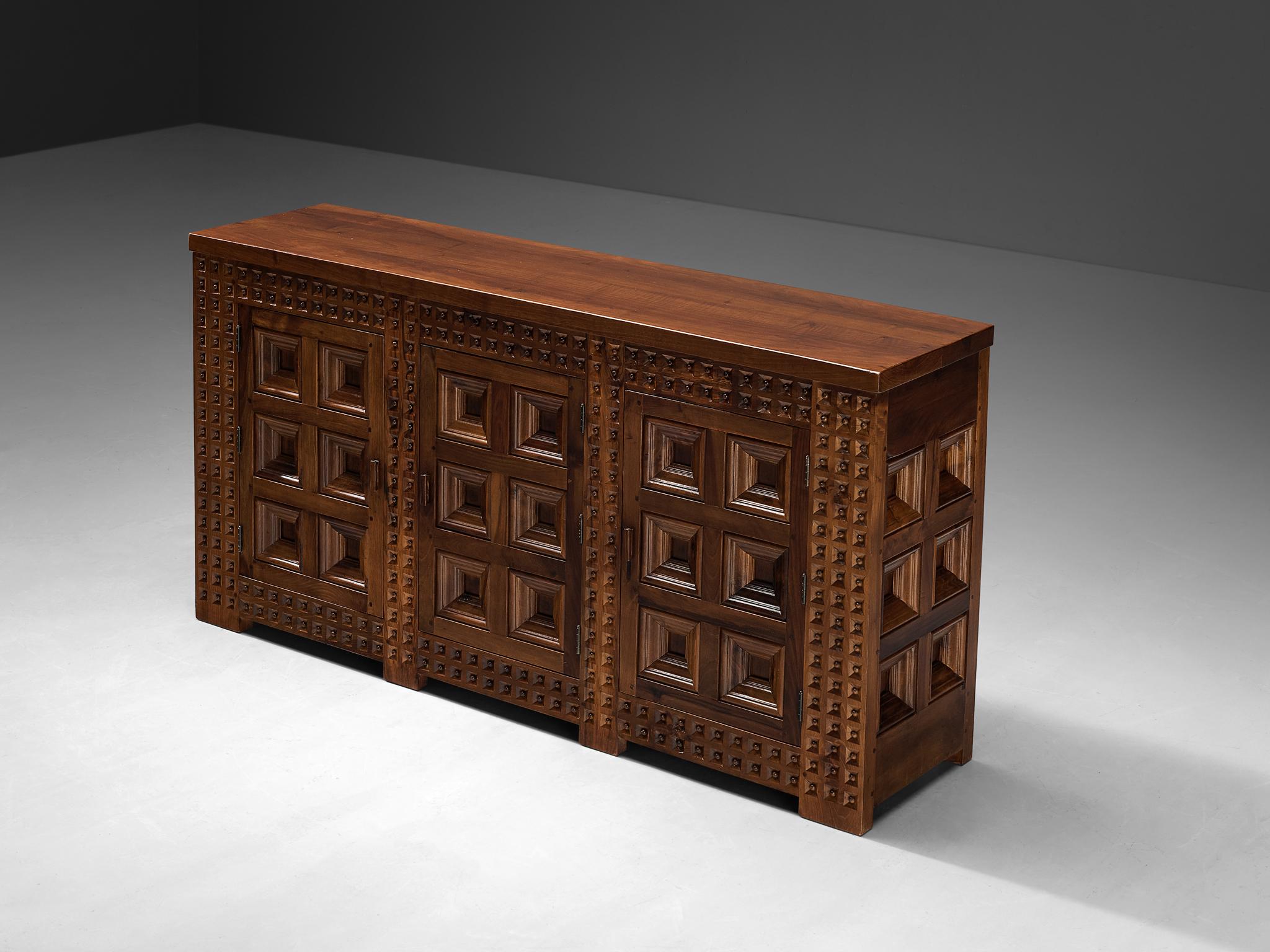 Sideboard, walnut, oak, Spain, 1960s 

This large cabinet originates from Spain and stylistically refers to the late 19th century Revival period. The embossed front is characterized by relief carvings with clearly defined squares. Its decorative