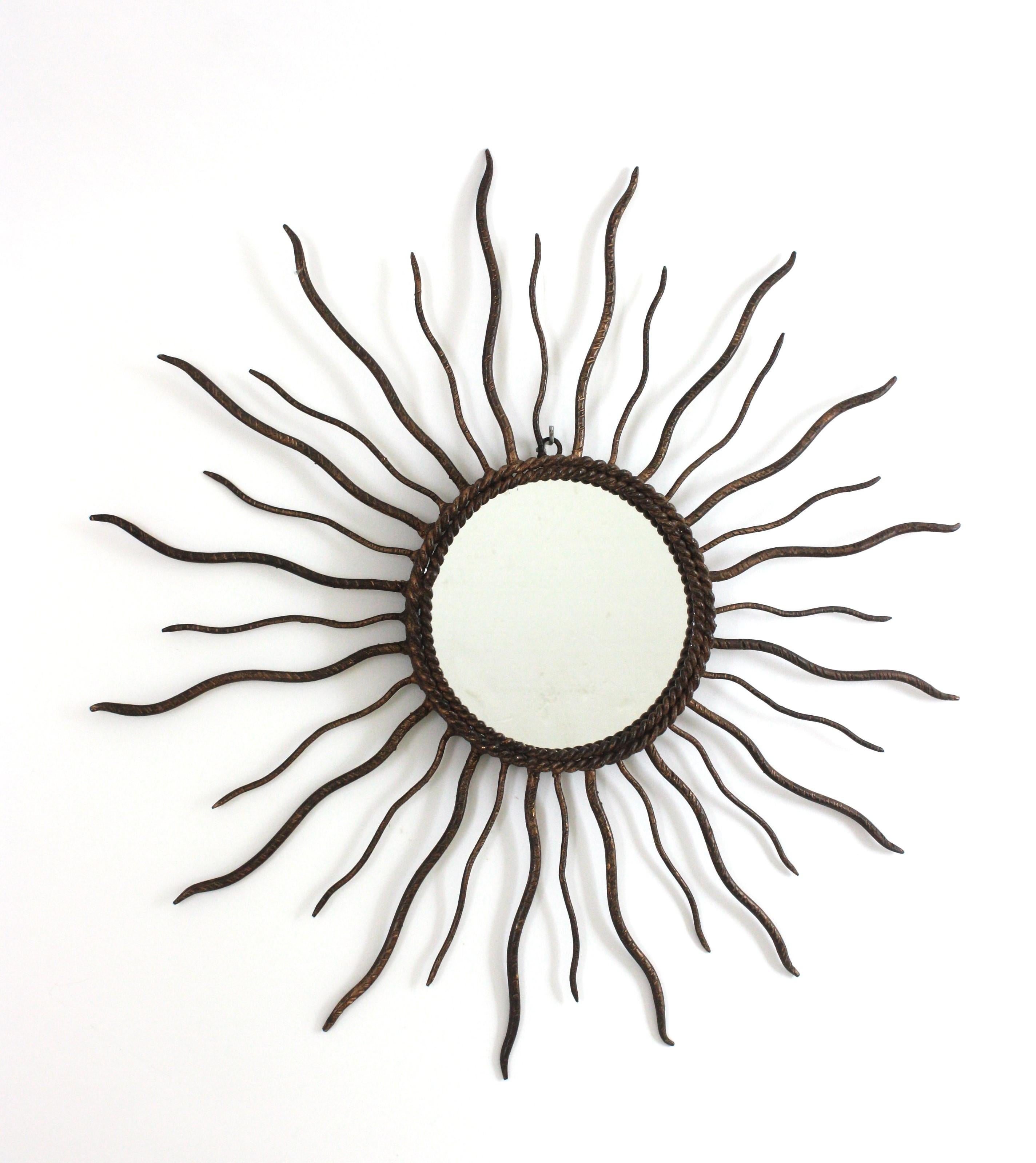 Parcel-Gilt Iron Sunburst Mirror
Sunburst Mirror in Wrought Iron and Brutalist Design. Spain, 1950s
This sunburst mirror was entirely made by hand. It has a frame with alternating iron thin rays in two sizes A double layered twisted iron rope