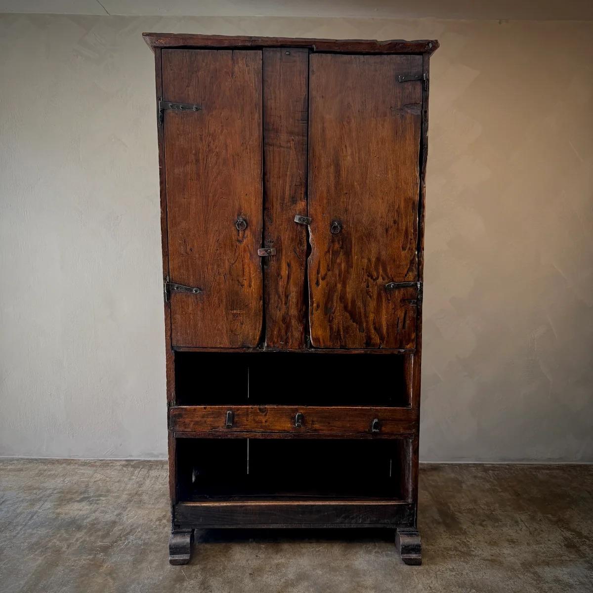 Questo mobile rustico vanta una struttura in legno robusto e invecchiato che richiama il fascino duraturo dell'artigianato spagnolo. Le sue grandi e robuste ante sono impreziosite da una tradizionale ferramenta in metallo che ne esalta l'aspetto