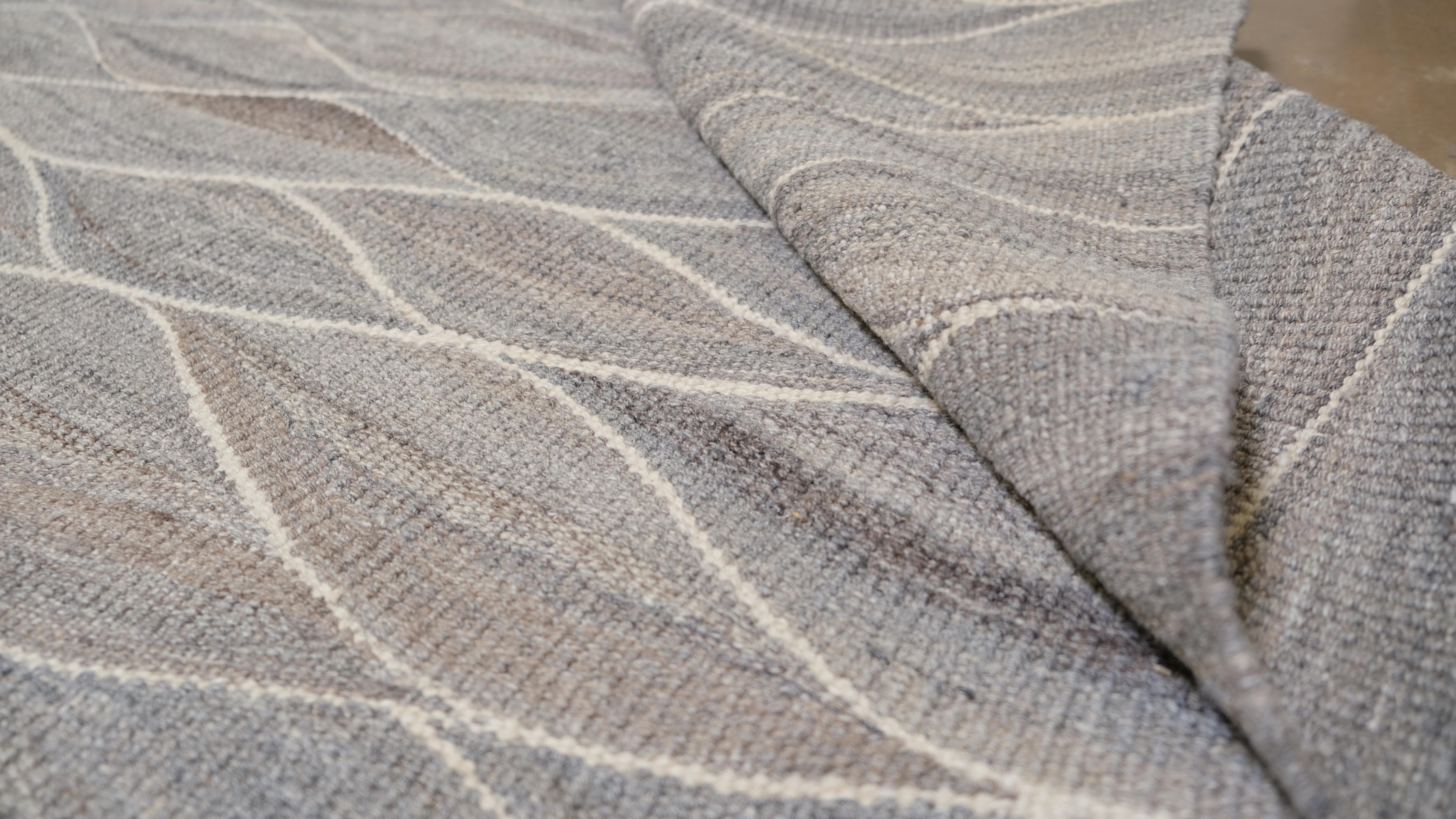 Esta sofisticada alfombra kilim de lana tejida a mano presenta un diseño contemporáneo de inspiración ondulada que encarna la elegancia y la fluidez. Con unas medidas de 11'9