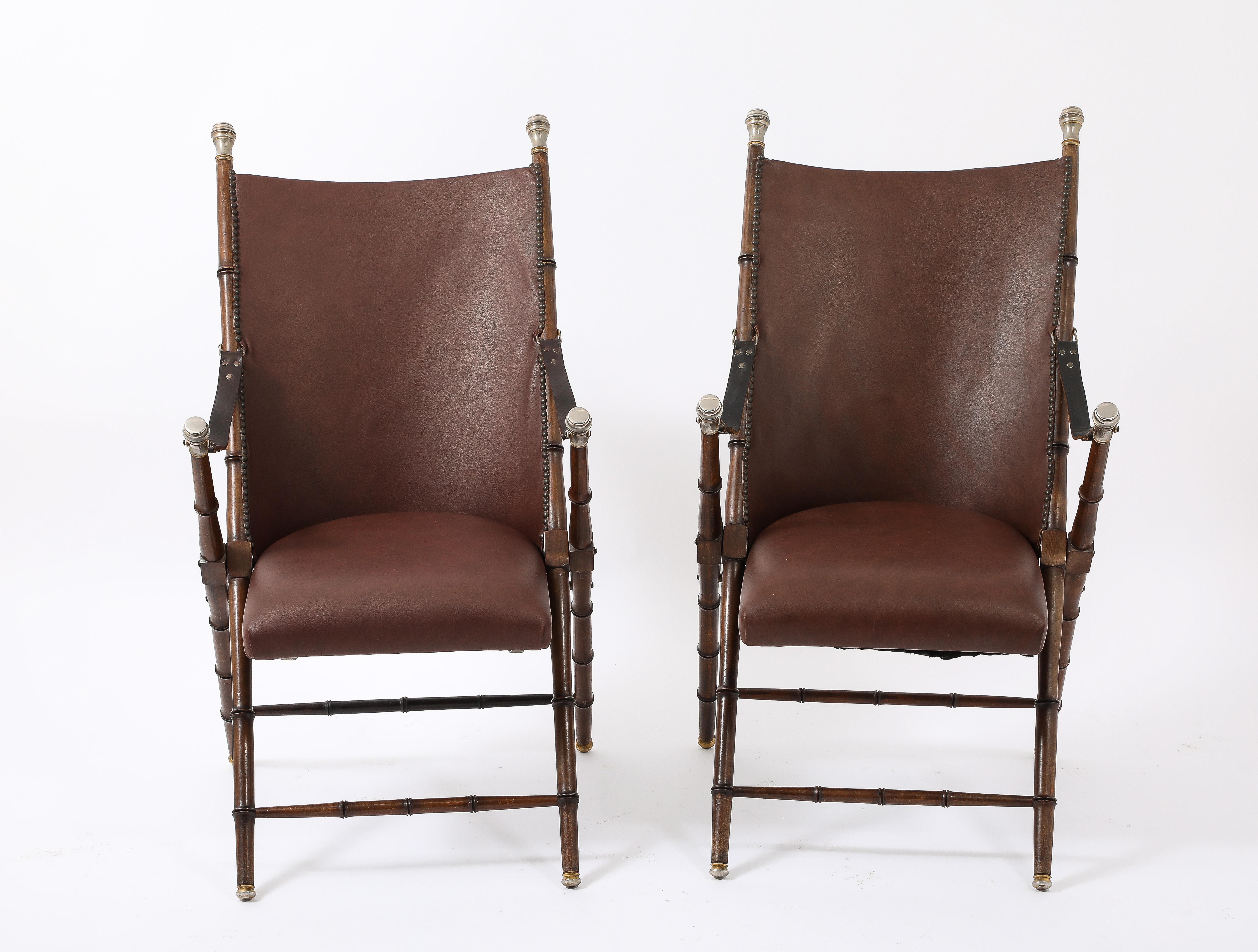 Elegant pair of folding campaign chairs in solid walnut imitating bamboo with solid brass hardware with original leather upholstery and nailhead details.
