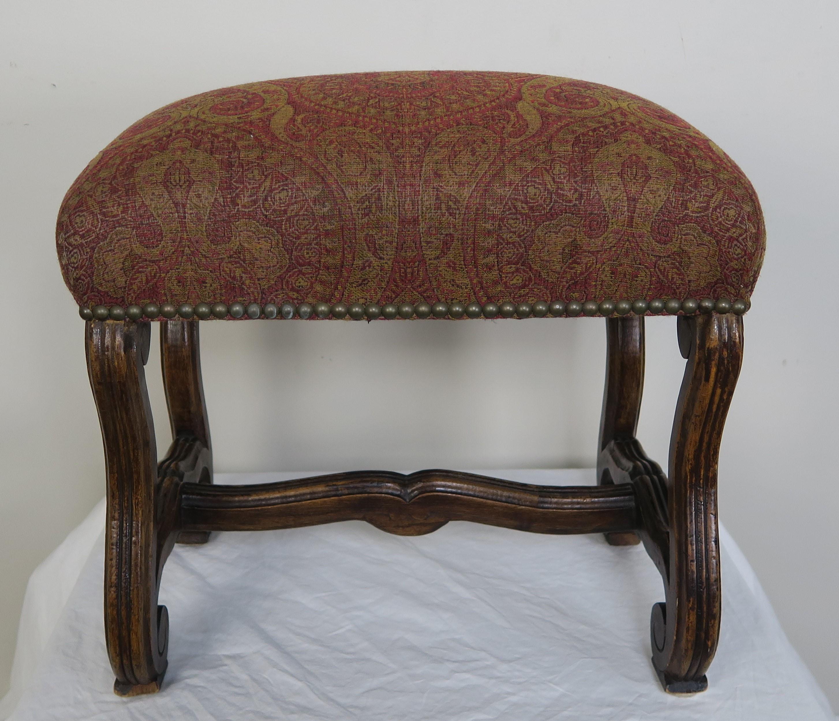 Spanish carved walnut bench upholstered in a paisley wool with antique brass nailhead trim detail.