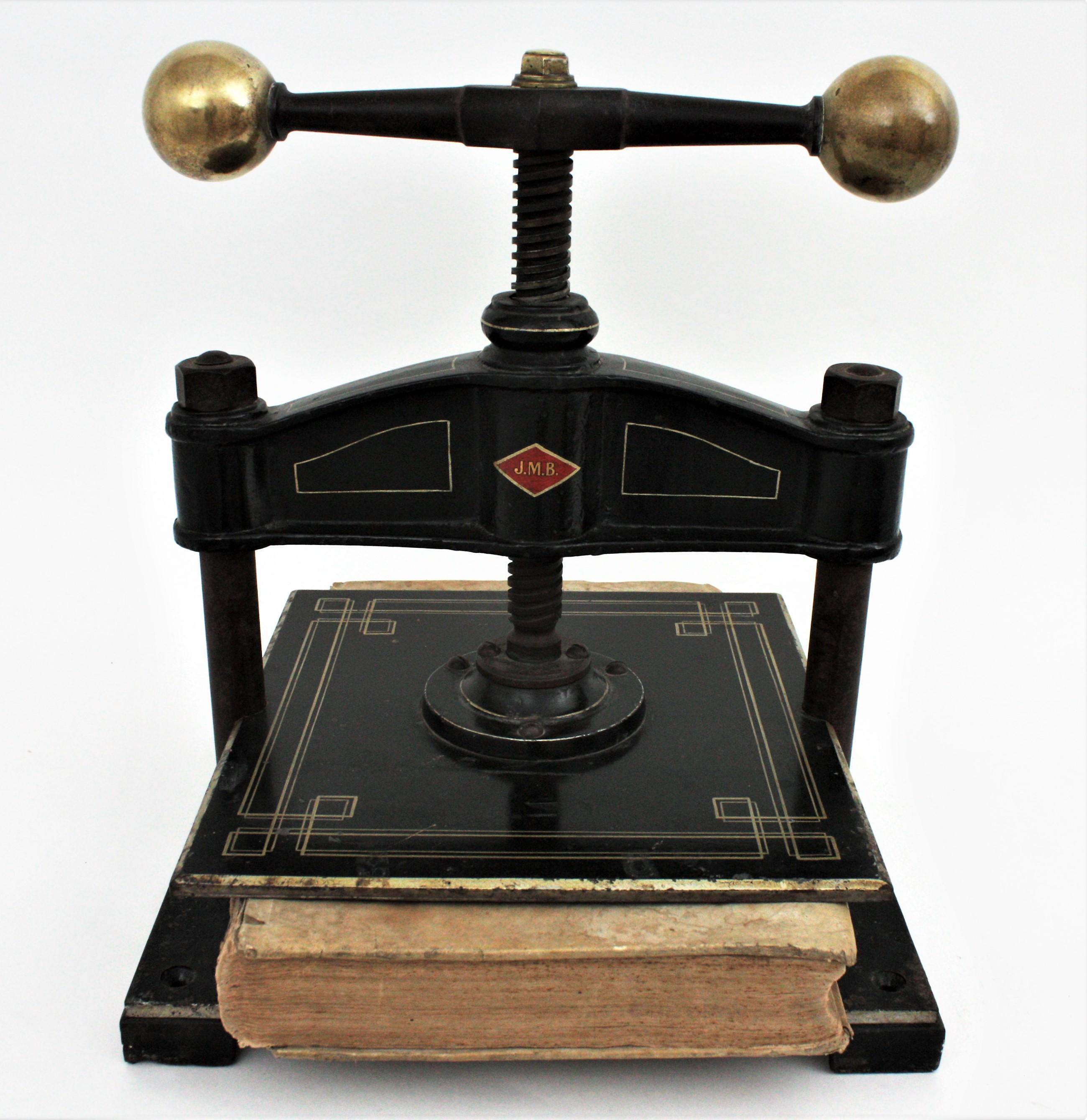 A large industrial black lacquered cast iron book-binding press with gold decoration and brass ball handles. Spain, 1900s.
Square base and golden ornamentations.
The iron press plate is connected to the manual screw controlled by wide handles. The