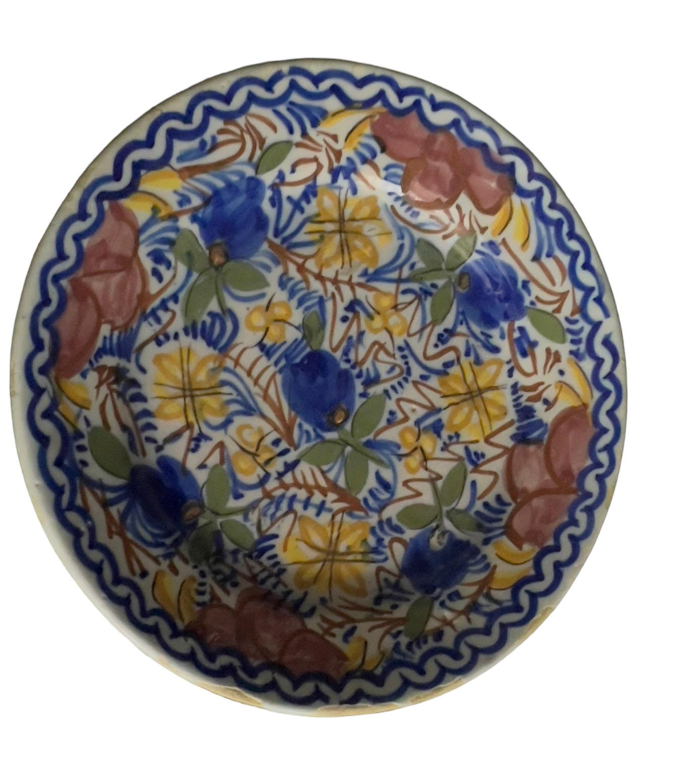 A vintage Spanish floral ceramic plate with blue, yellow red and green flowers. Circa 1960s.