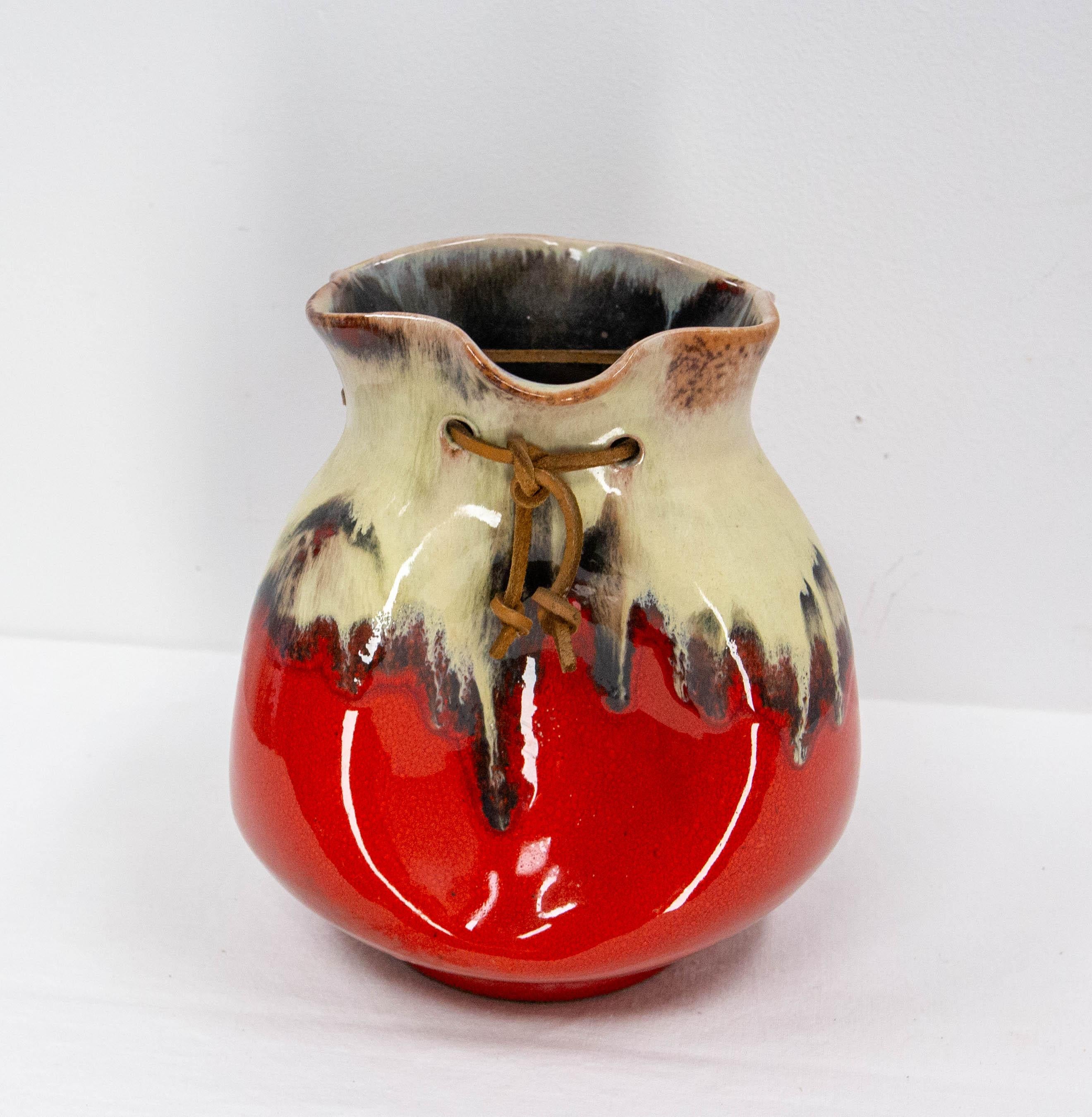 Vaso in ceramica smaltata bianca e rossa realizzato nel 1960 circa.
Questo vaso ha un lato giocoso grazie alla sua forma di borsetta molto ben imitata. È ornato da un cordone di pelle.
Questo stile di vaso ricorda le ceramiche di Vallauris