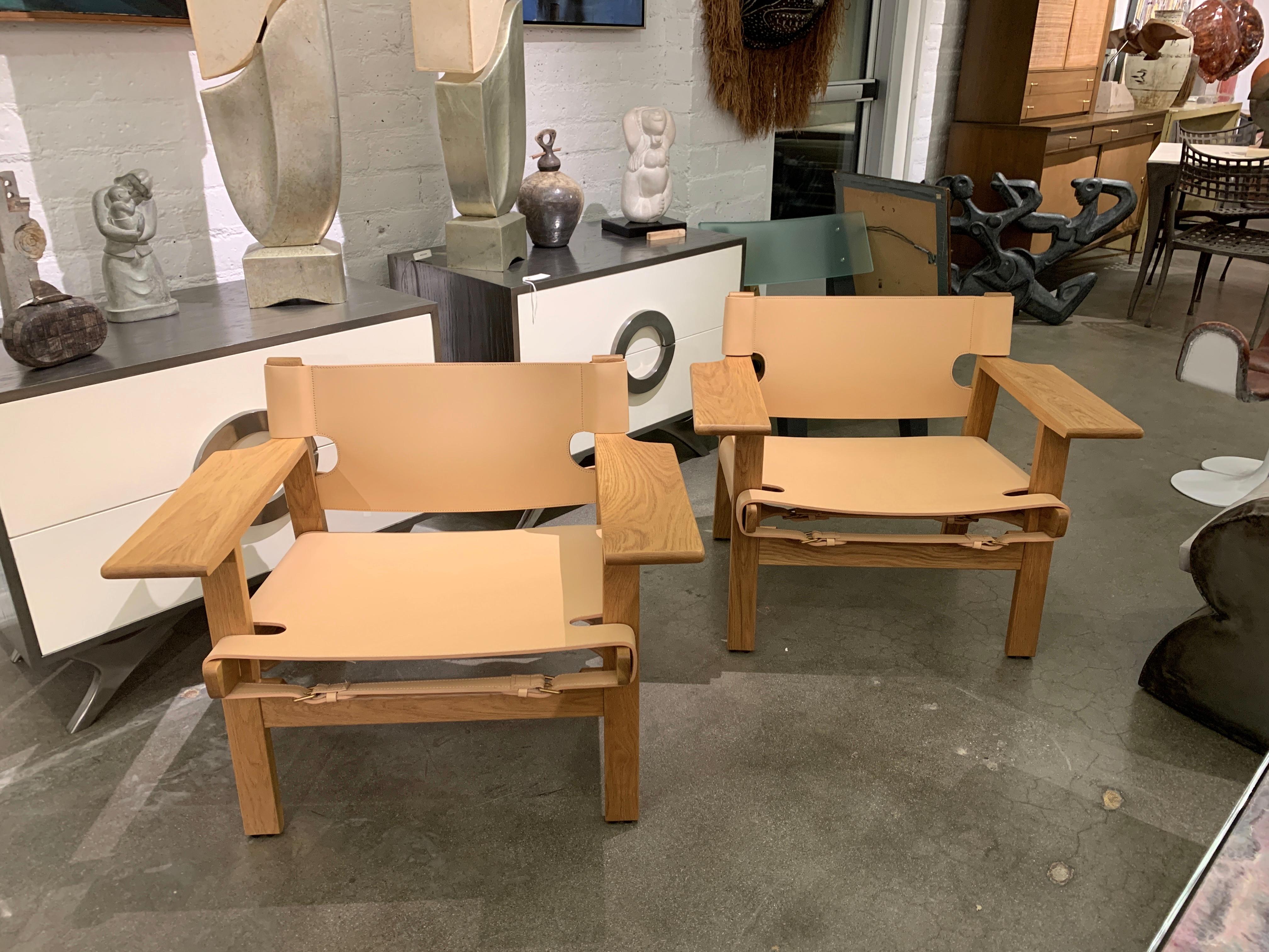 A pair of Spanish chairs designed by Borge Mogensen. These chairs bear no label other than the brass buckles being marked Gucci. They are constructed of highly figured oak and thick leather. The brass buckles are marked Gucci. Dimensions are the