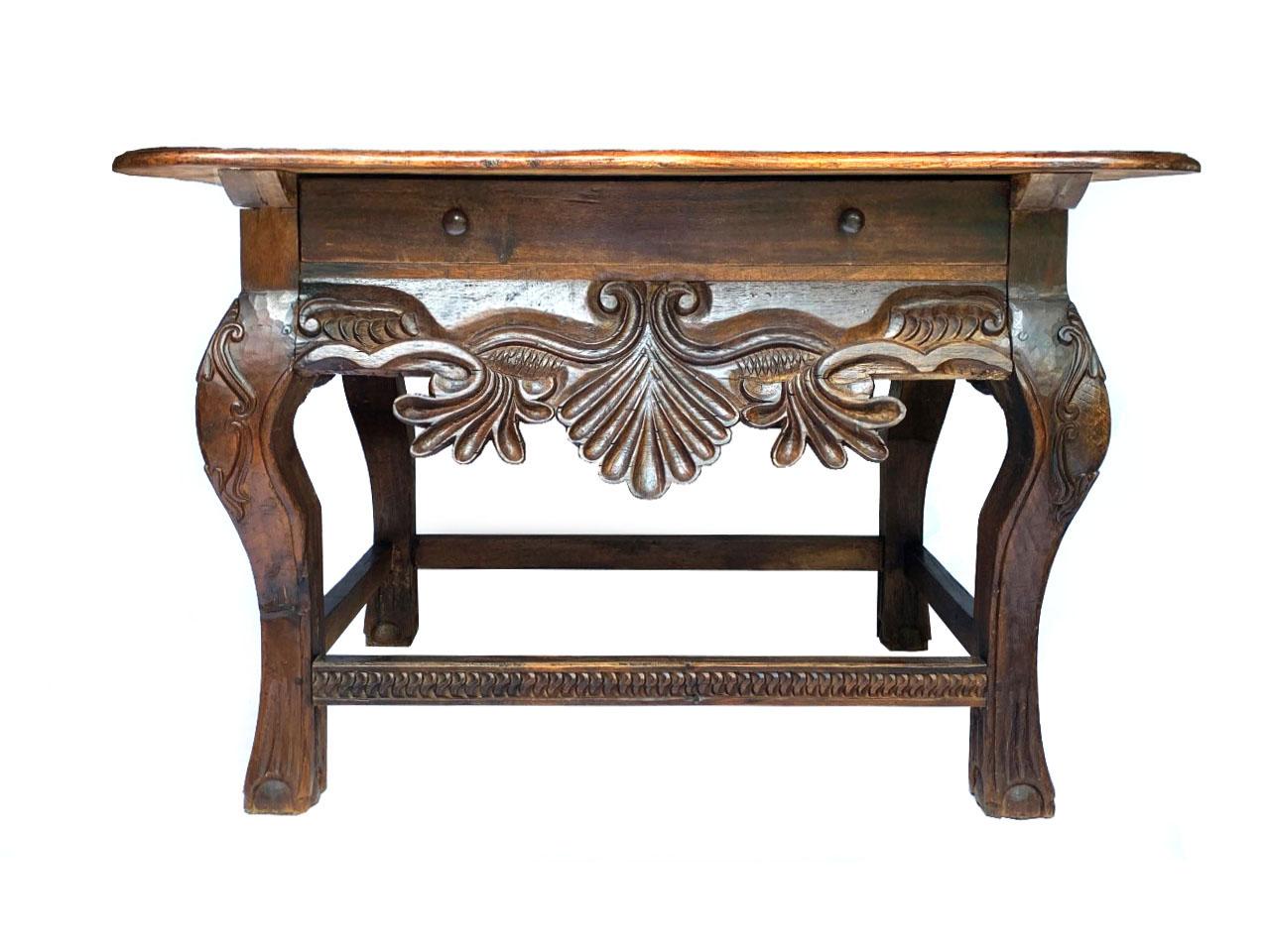 Outstanding Spanish Colonial 18th Century Presentation Hall Table 
Richly carved with motifs of shells, rocailles and scrolls. 
Arched sturdy legs carved with palm and scroll motifs. 
Table top with wavy edges over a large drawer with turned wooden