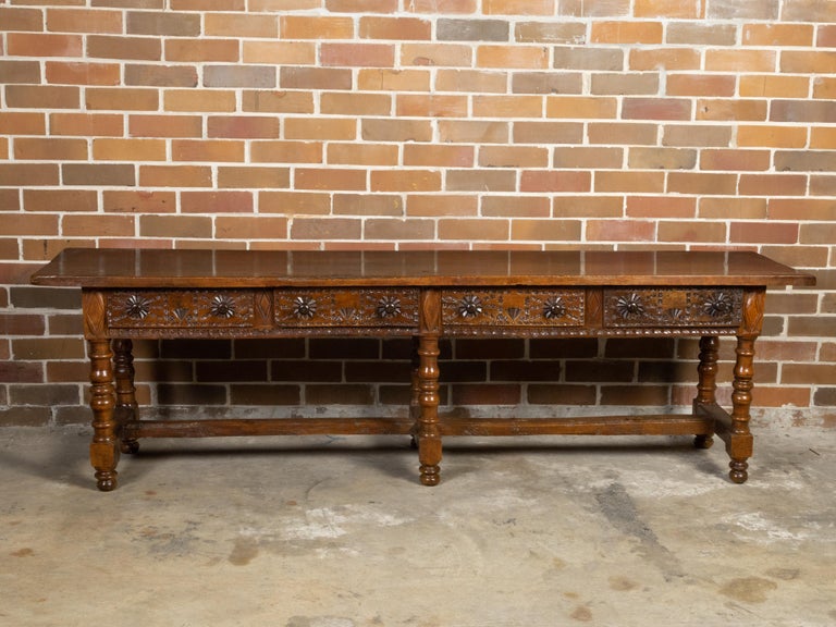 A Spanish Colonial walnut server table from the 18th century, with four drawers, richly carved décor, turned legs and nice patina. Crafted from walnut during the 18th century, this Spanish Colonial table features a long and narrow rectangular top