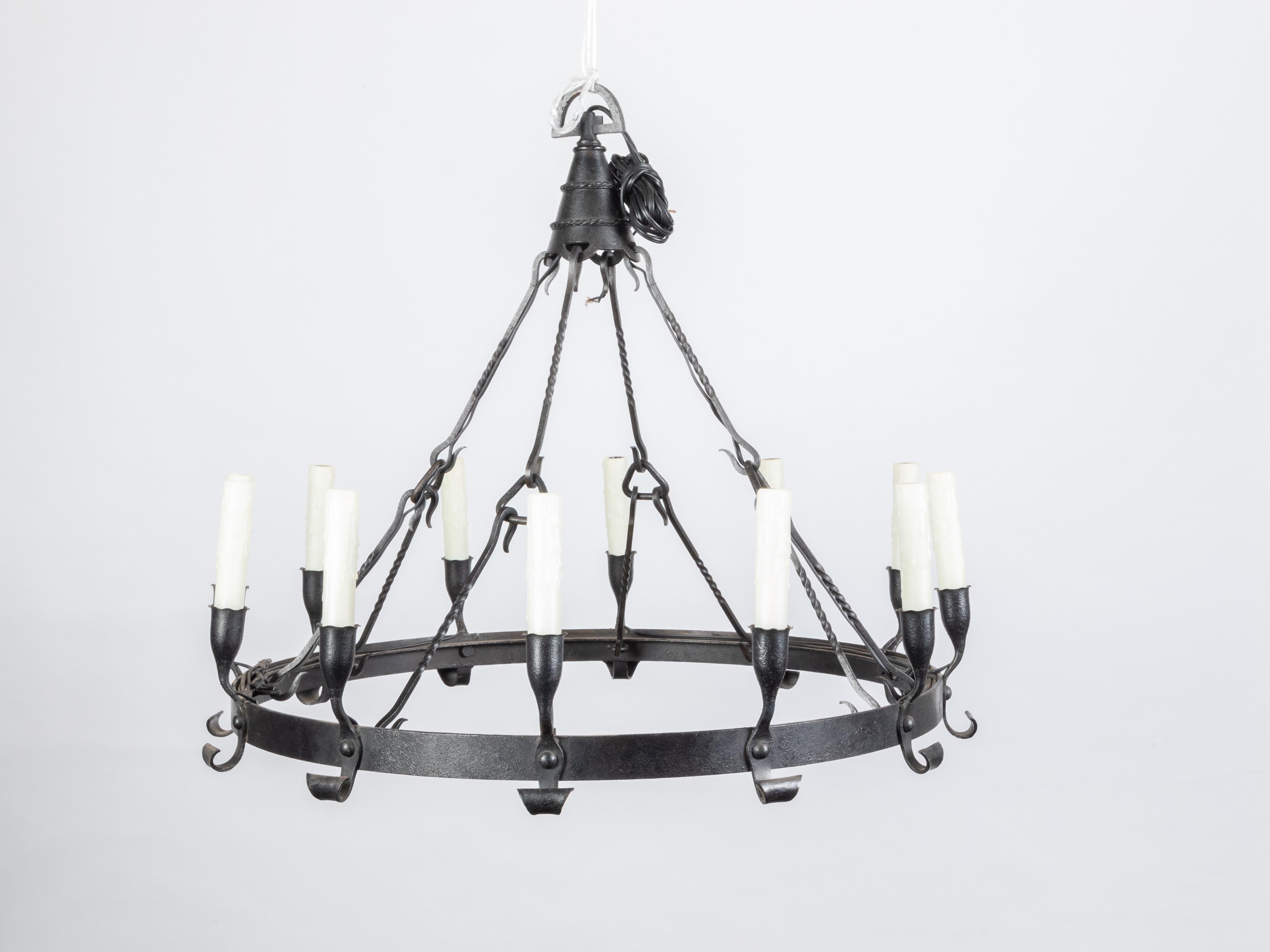 A Spanish Colonial iron chandelier from the early 20th century, with 12 arms and central ring. Created in the early years of the 20th century, this Spanish Colonial chandelier features an iron ring supporting 12 arms with scrolling accents in the