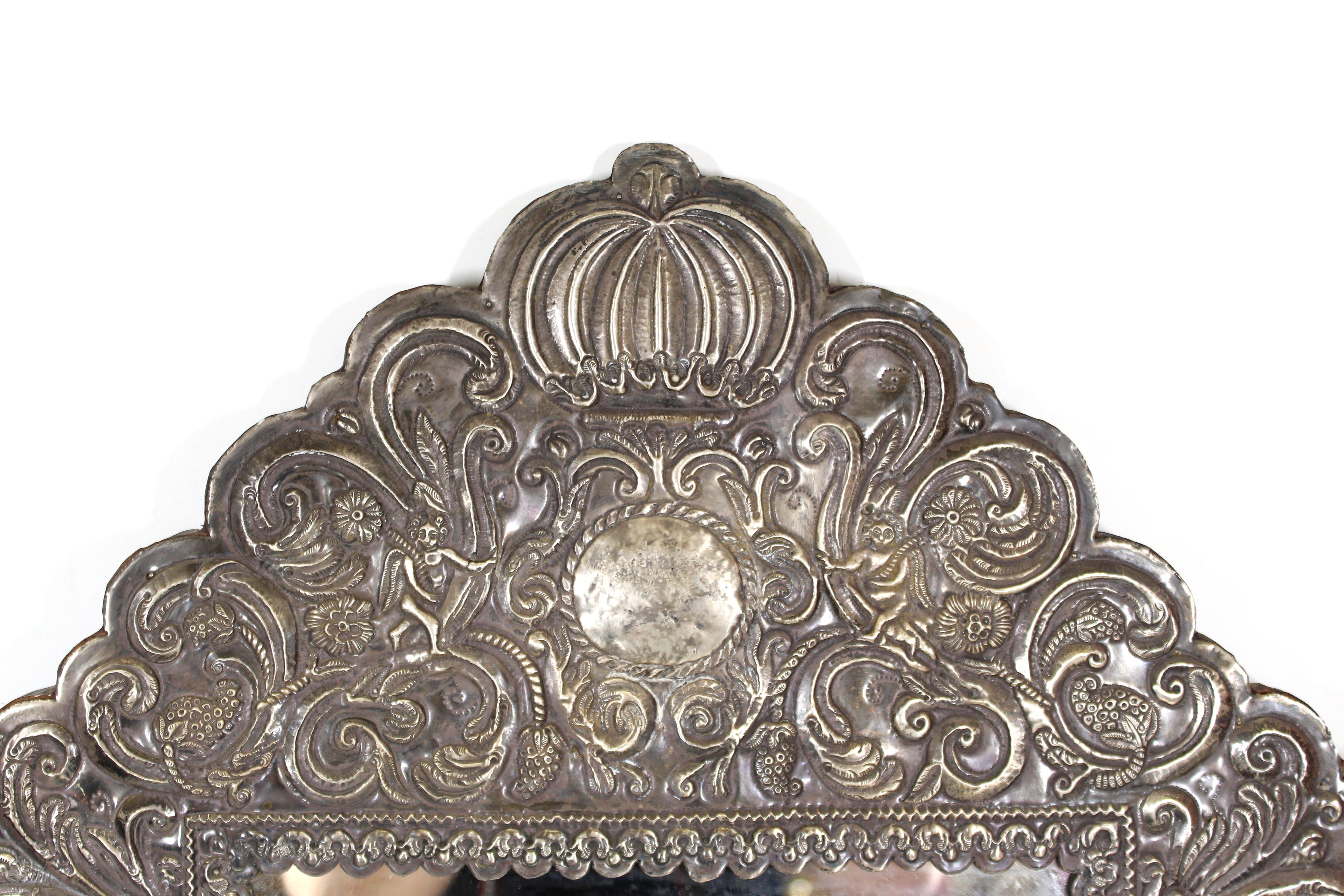 Spanish Colonial Baroque elaborate mirror frame in repoussé silver on wood frame. The piece has a vast amount of details with volutes and foliage, angels, mermaids, allegories, parrots and a crowning crest on the top. handmade during the late