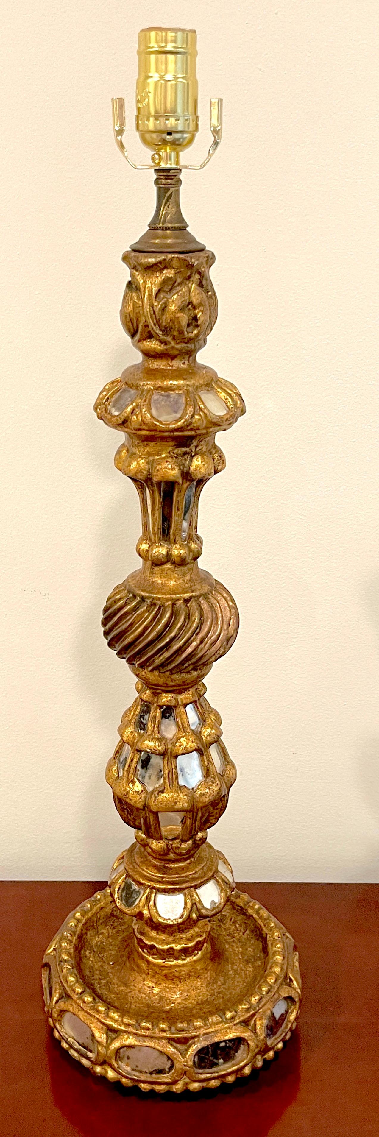 Spanish Colonial giltwood & mirror candlestick, now as a lamp.
Spain, circa 1960s.

A nice example, finely carved and gilt, of tall undulating candlestick form, with numerous inlays of mosaic mirror.
Newly rewired. Ready to shade and place.