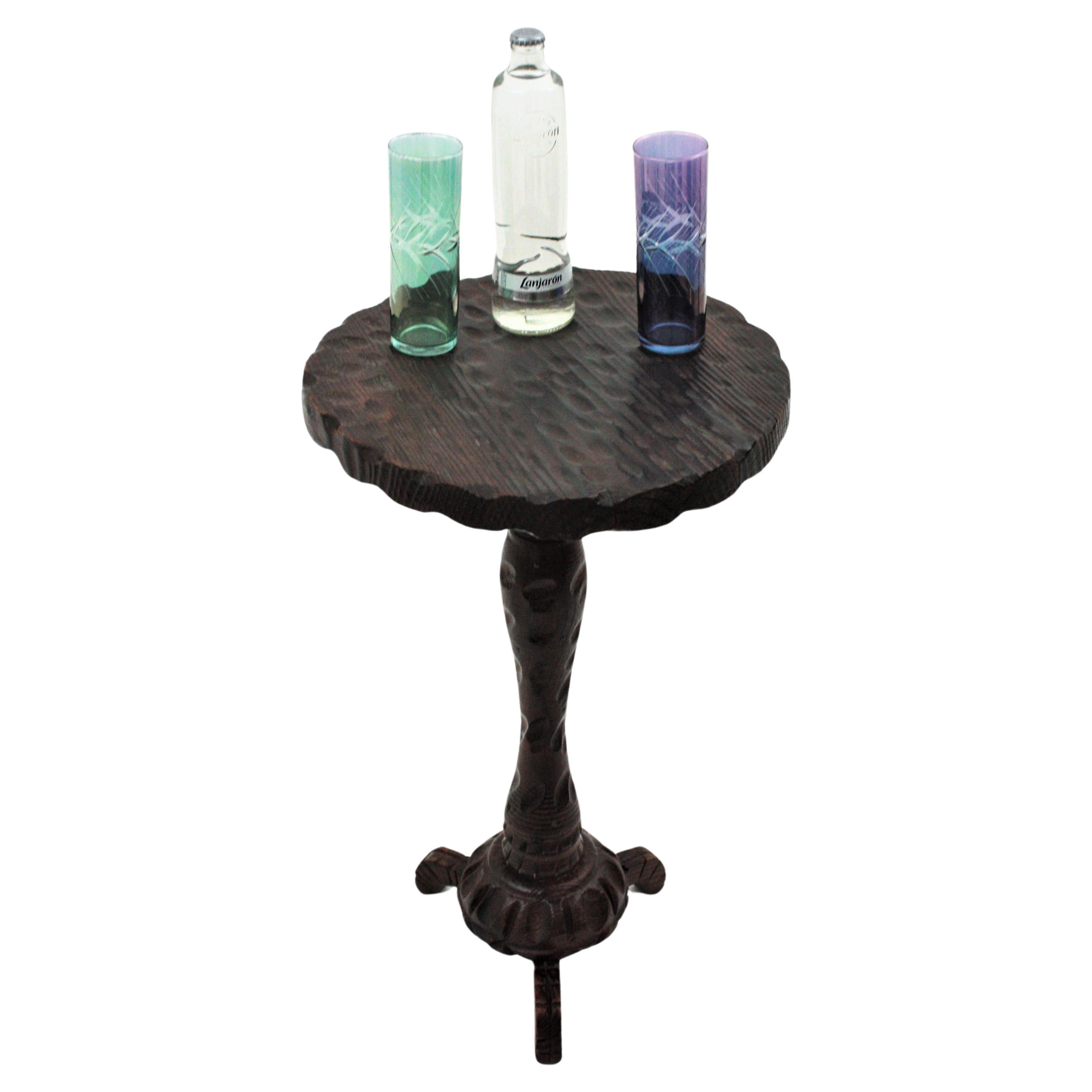 Handcarved pine wood gueridon table or occassional table standing on tripod base. Spain, 1940s.
The tabletop in round shape has scalloped details on the edge and beautiful carvings thorough. It is supported on a wood stem with scalloped details and