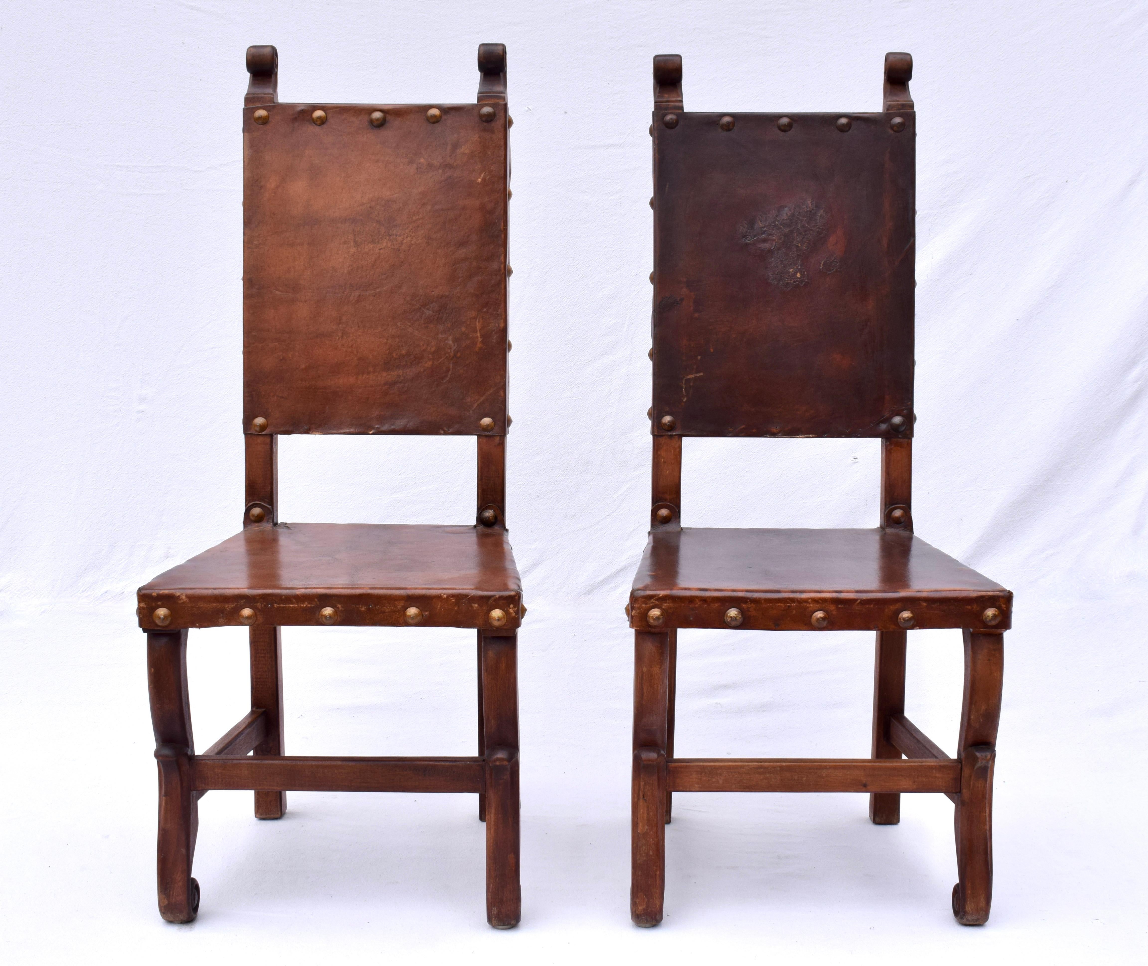 Fabulous  pair of carved wood dining chairs with thick leather seats & backs embellished with brass nail heads in the Spanish Colonial style. Gorgeous rock solid condition ready for use.