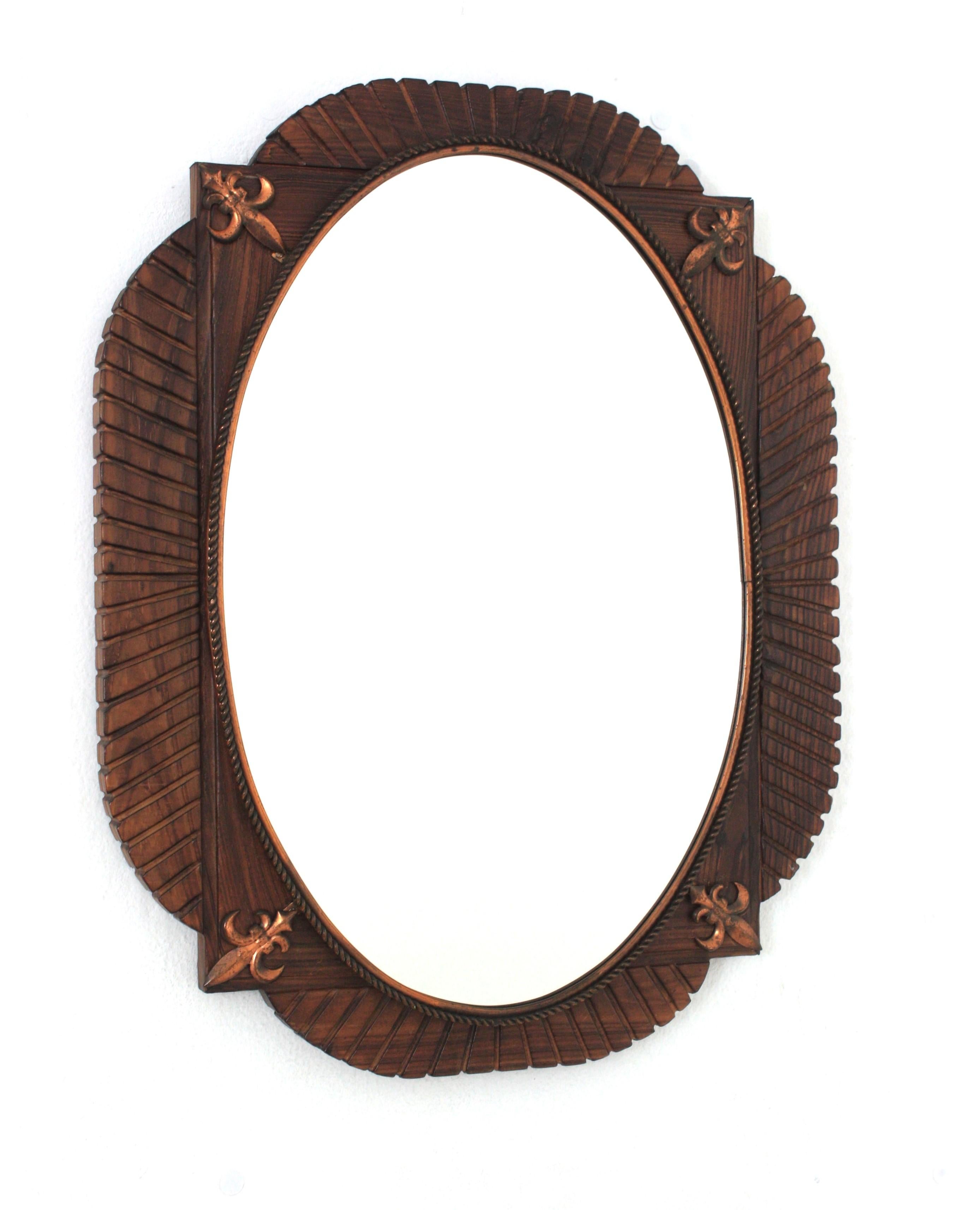 Espejo de pared ovalado de madera de pino tallada a mano con detalles de flor de lis de cobre, España, años 40.
Este espejo de pared tiene un marco festoneado de madera que rodea un cristal central ovalado con un dibujo de cobre retorcido. Detalles
