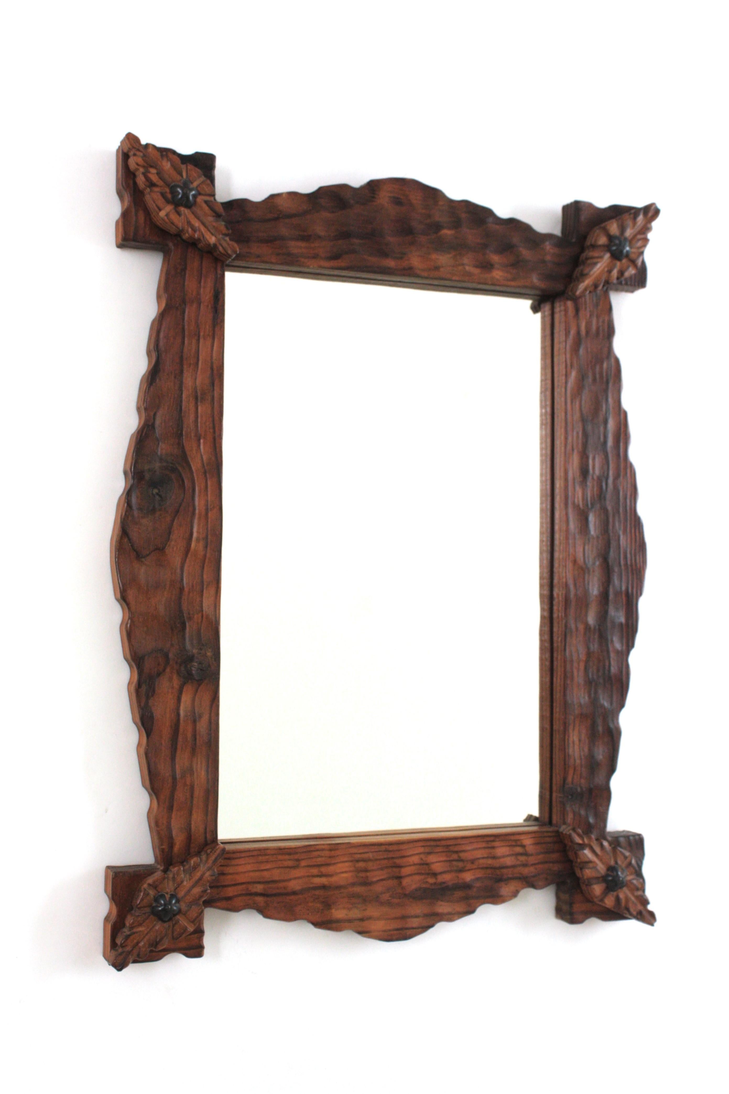 Hand carved pine wood rectangular mirror with stepped out corner details and iron studs, Spain, 1940s.
This mirror features a wooden scalloped frame with rhombus decorative details on the corners surrounding a central rectangular glass.The frame is
