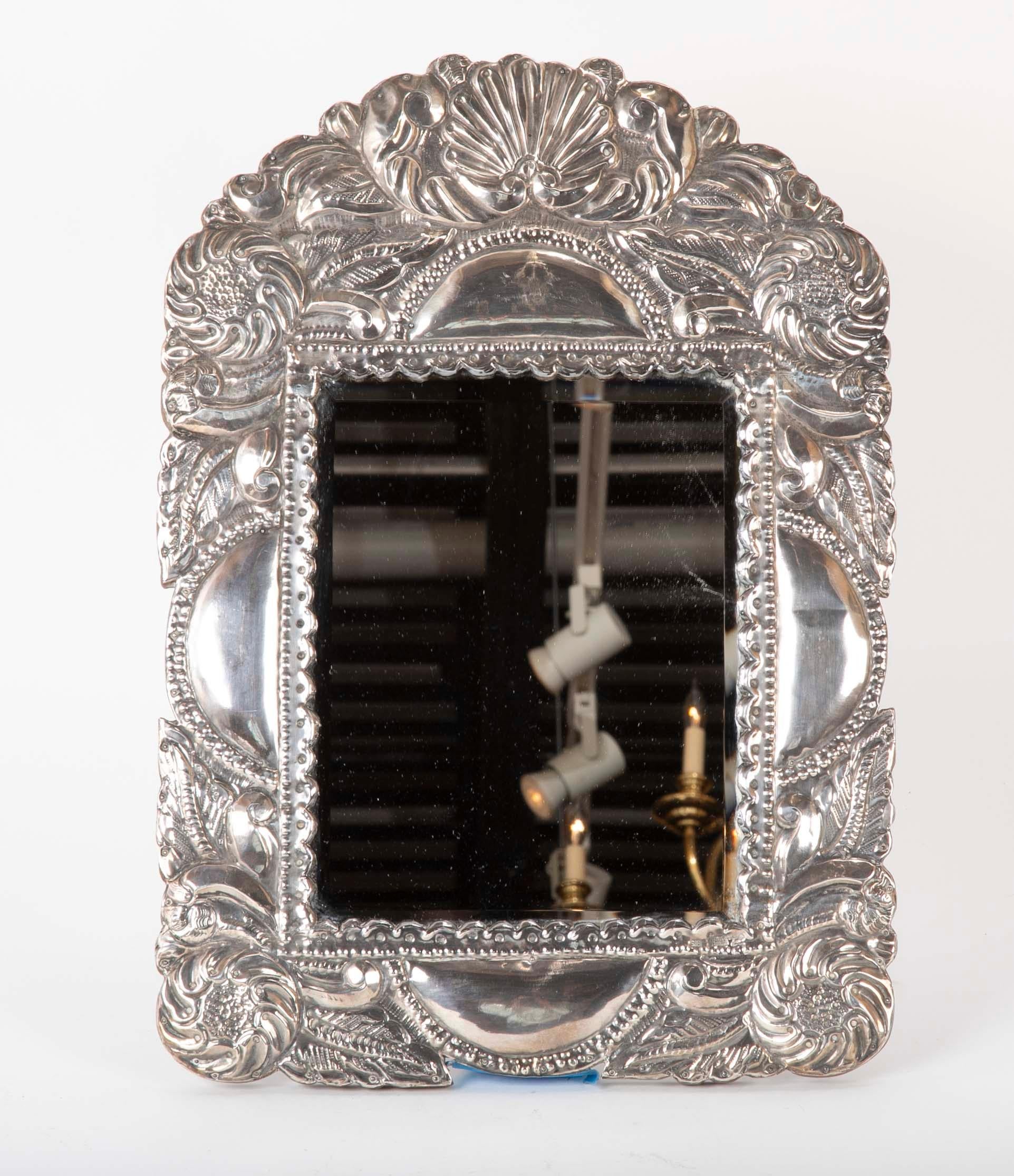 A Peruvian silver repousse picture frame or table top mirror. Hand worked in the Spanish Colonial style decorated in floral and shell motifs. This is a wonderful looking and distinct vanity mirror that will also make a great frame for that favorite
