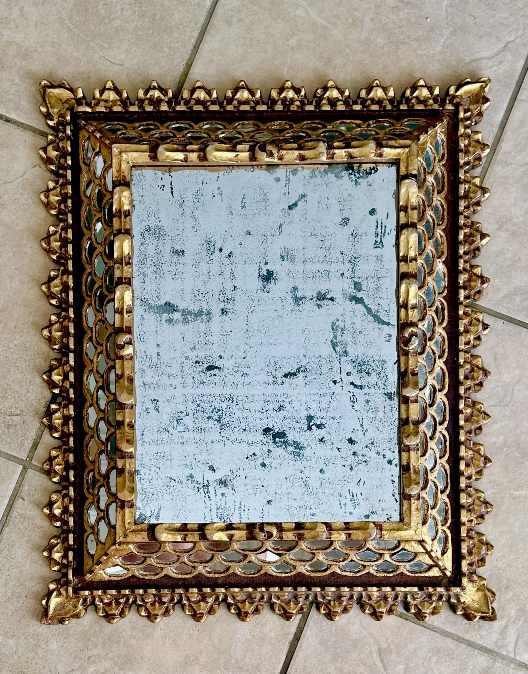 Spanish Colonial style wall mirror in gold giltwood and gesso finish. Center mirror has lots of antiqued age spots and oxidation. 
The larger center mirror is 14.5