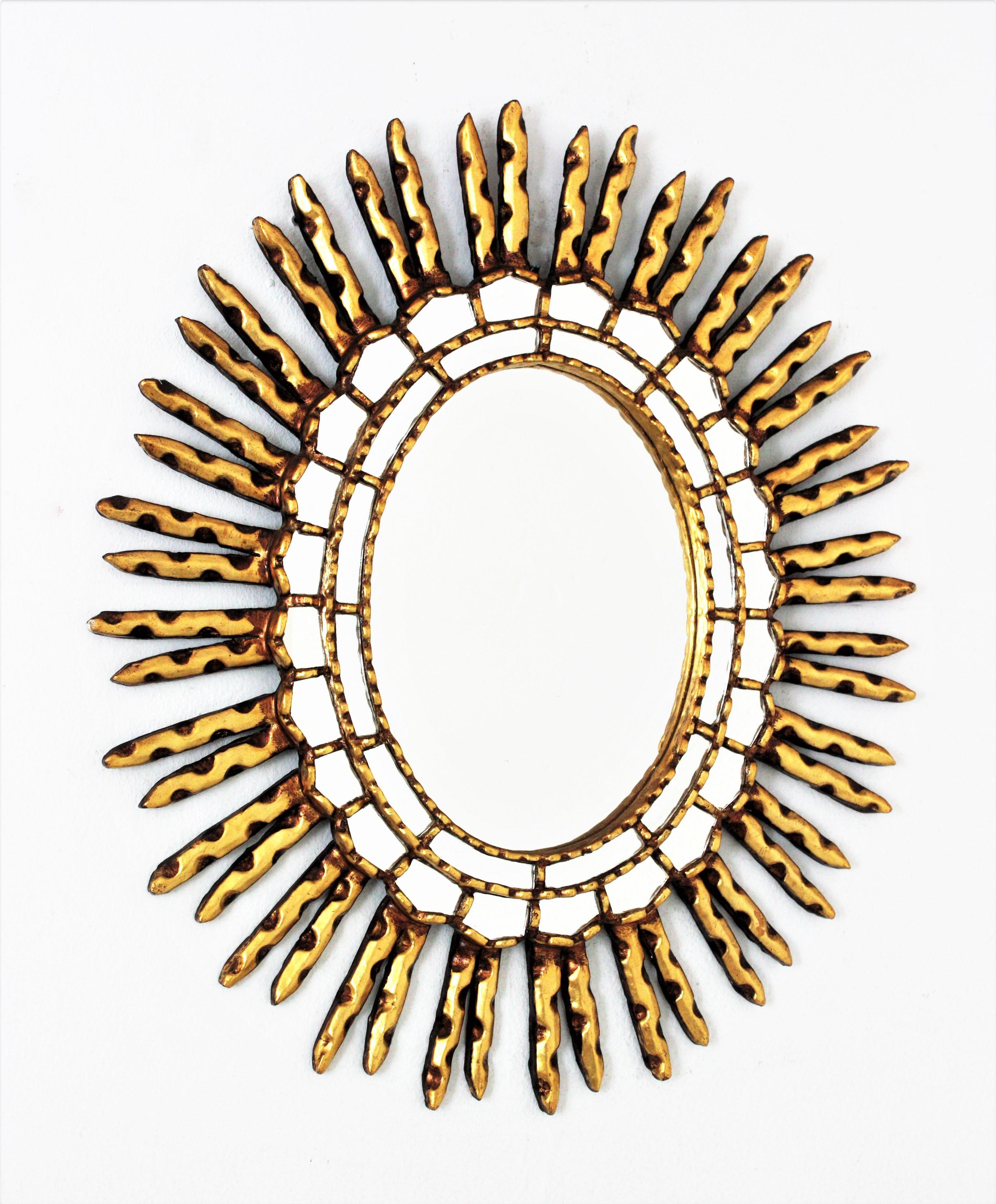 Spanish Colonial style gilt wood oval sunburst mirror with mirror insets in the frame, 1950s-1960s
This eye-catching sunburst mirror was manufactured at the Midcentury period in the style of Spanish Colonial. It has two layers of mosaic small