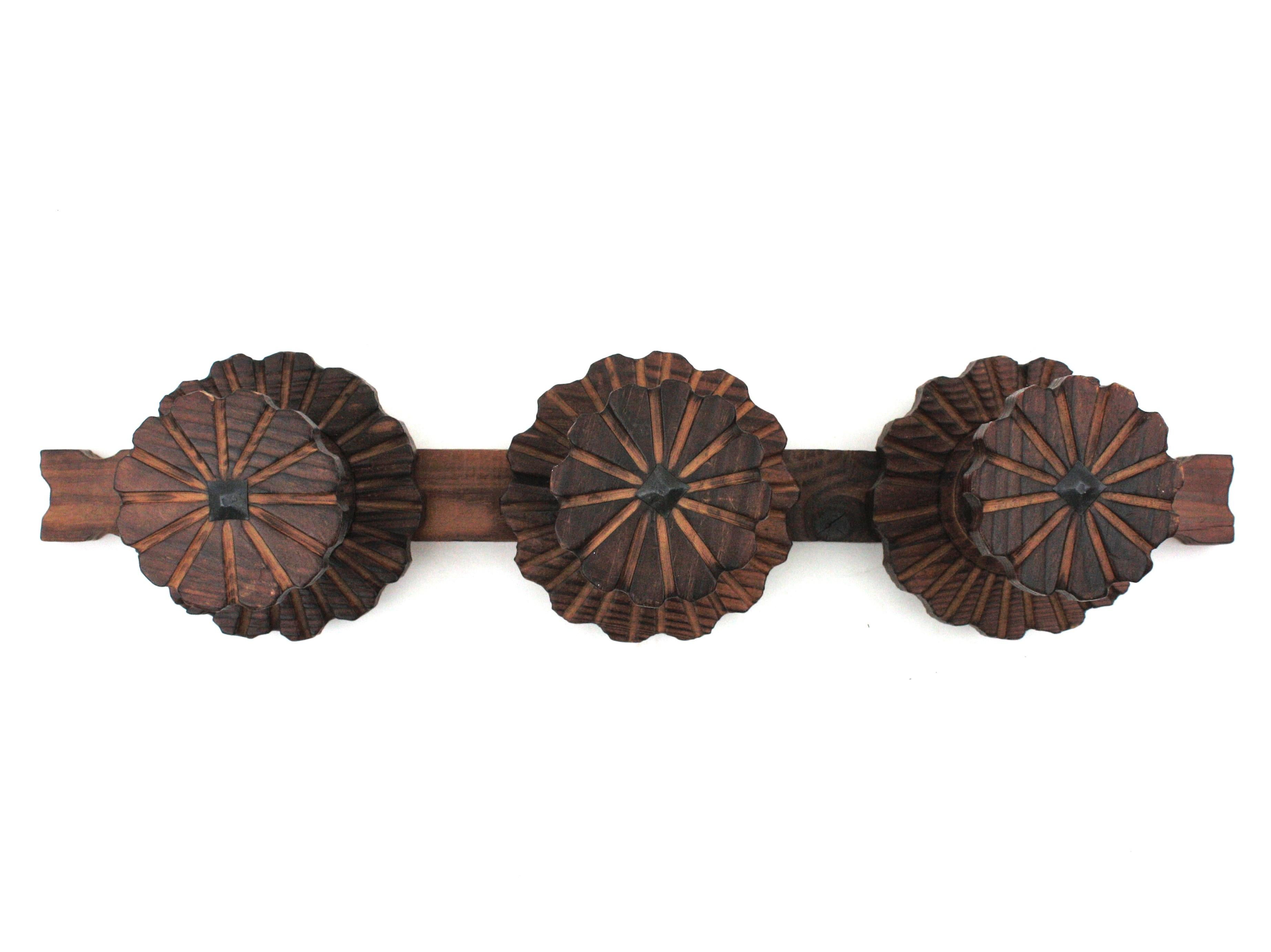 Handcarved pine wood wall coat rack, 3 hangers, Spain, 1940s.
This eye-catching coat rack has 3 flower shaped hangers with beautifully carved backplates and striped details.
It has a rustic finish and spanish colonial accents.
To be used a wall coat