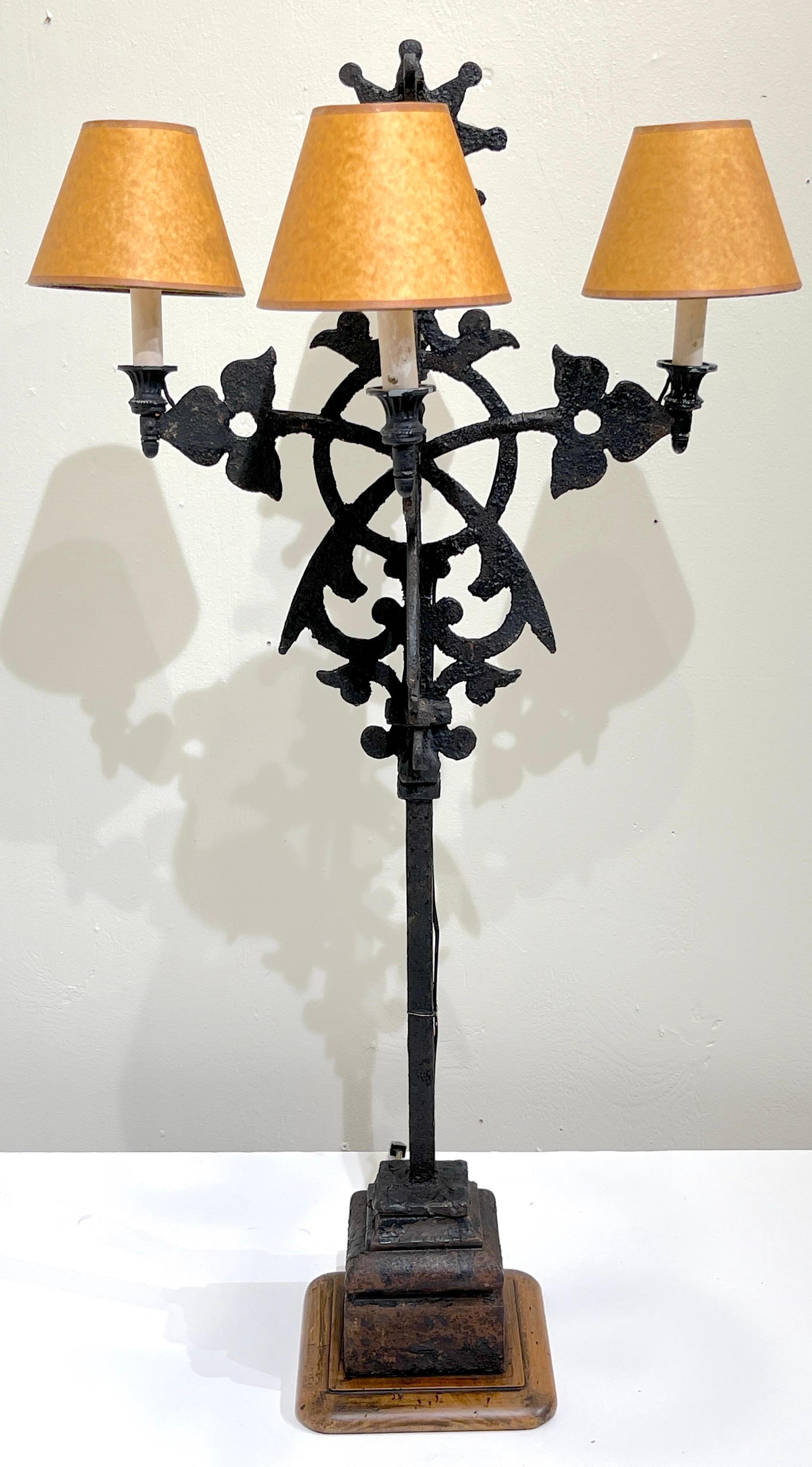 Spanish Colonial wrought iron sunburst Motif four-light candelabra, electrified
19th/20th century now electrified
Complete with four Parchment lamp shades 

Standing tall, this impressive rustic wrought iron sculptural candelabra, with
