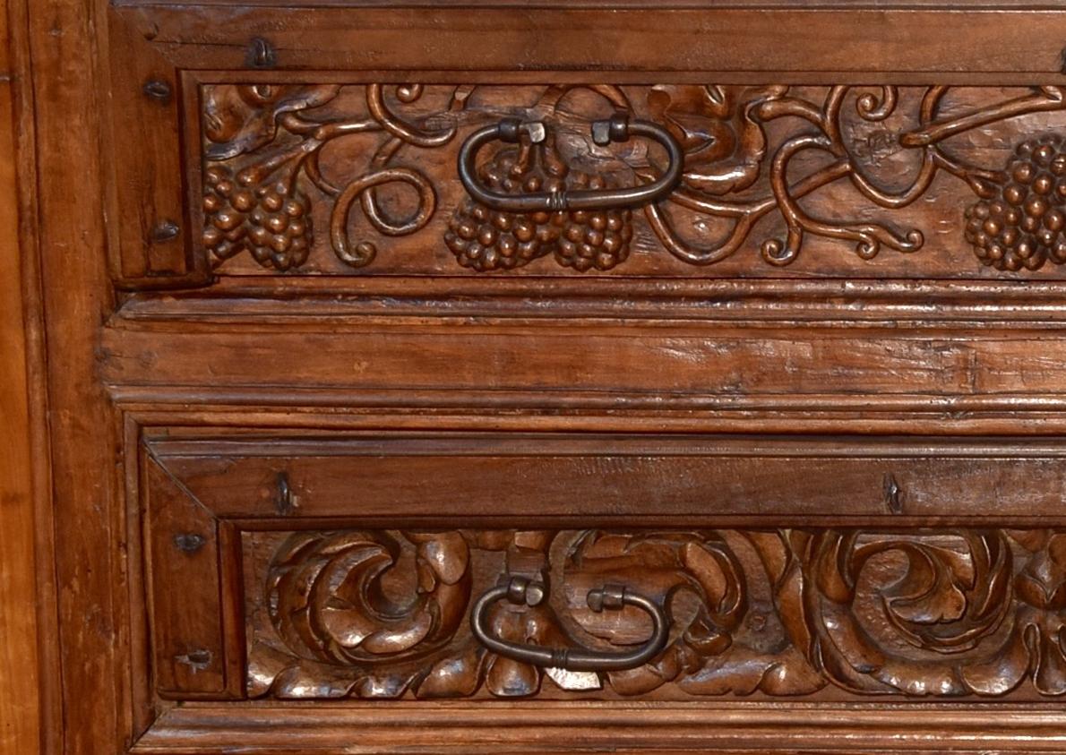 Commode en bois de noyer à décor sculpté. Espagne, XVIIe siècle. 
Armoire à trois tiroirs très profonds, dont un plus bas, sur pieds rectangulaires et avec plateau supérieur droit en bois, légèrement en saillie. Chacun des tiroirs comporte deux