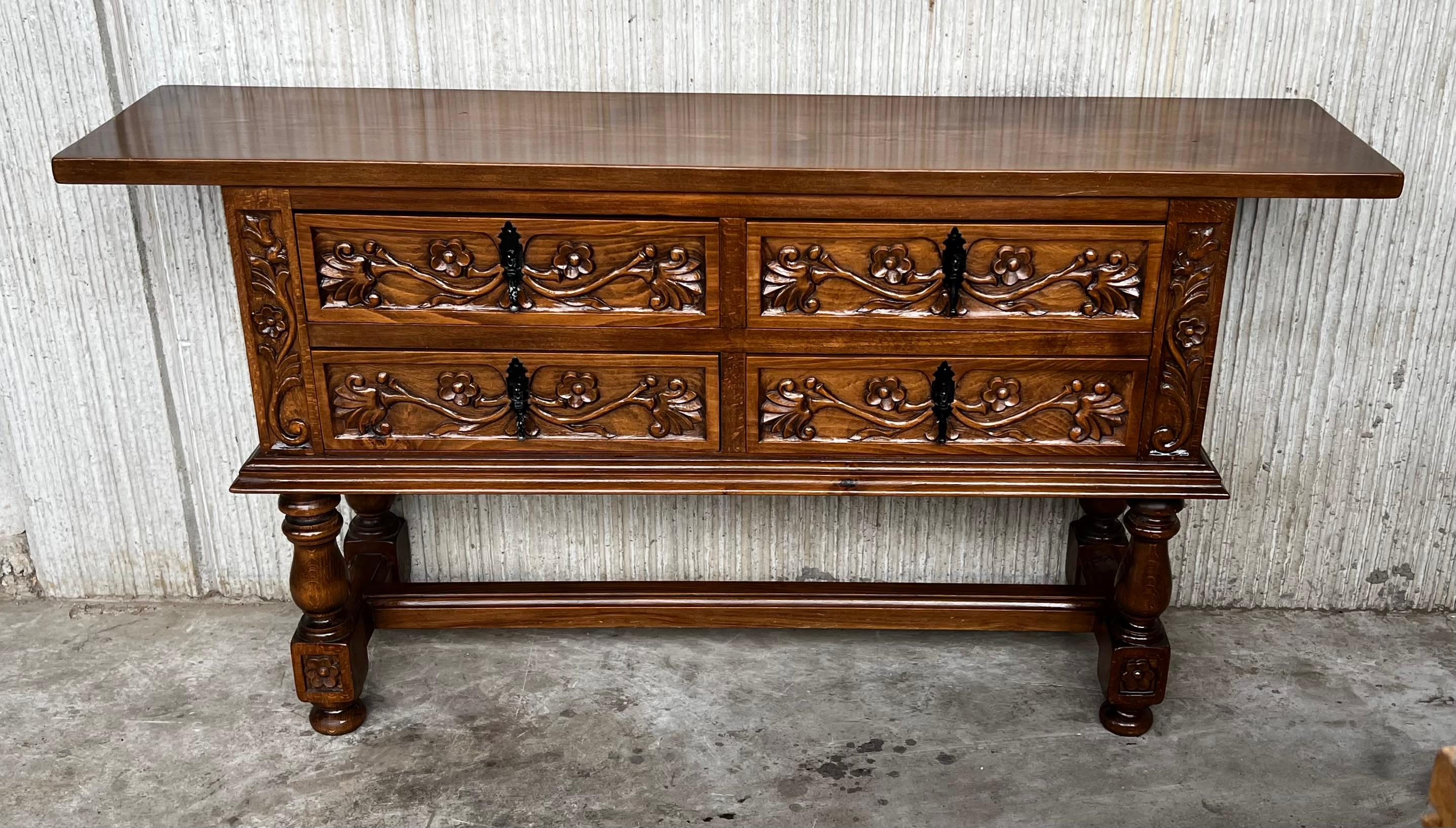This large Spanish early 20th century features a beautiful one plank rectangular top over four wide carved drawers. Each drawer, featuring slightly different hardware, is adorned with floral motifs and each drawer with their original handmade drop
