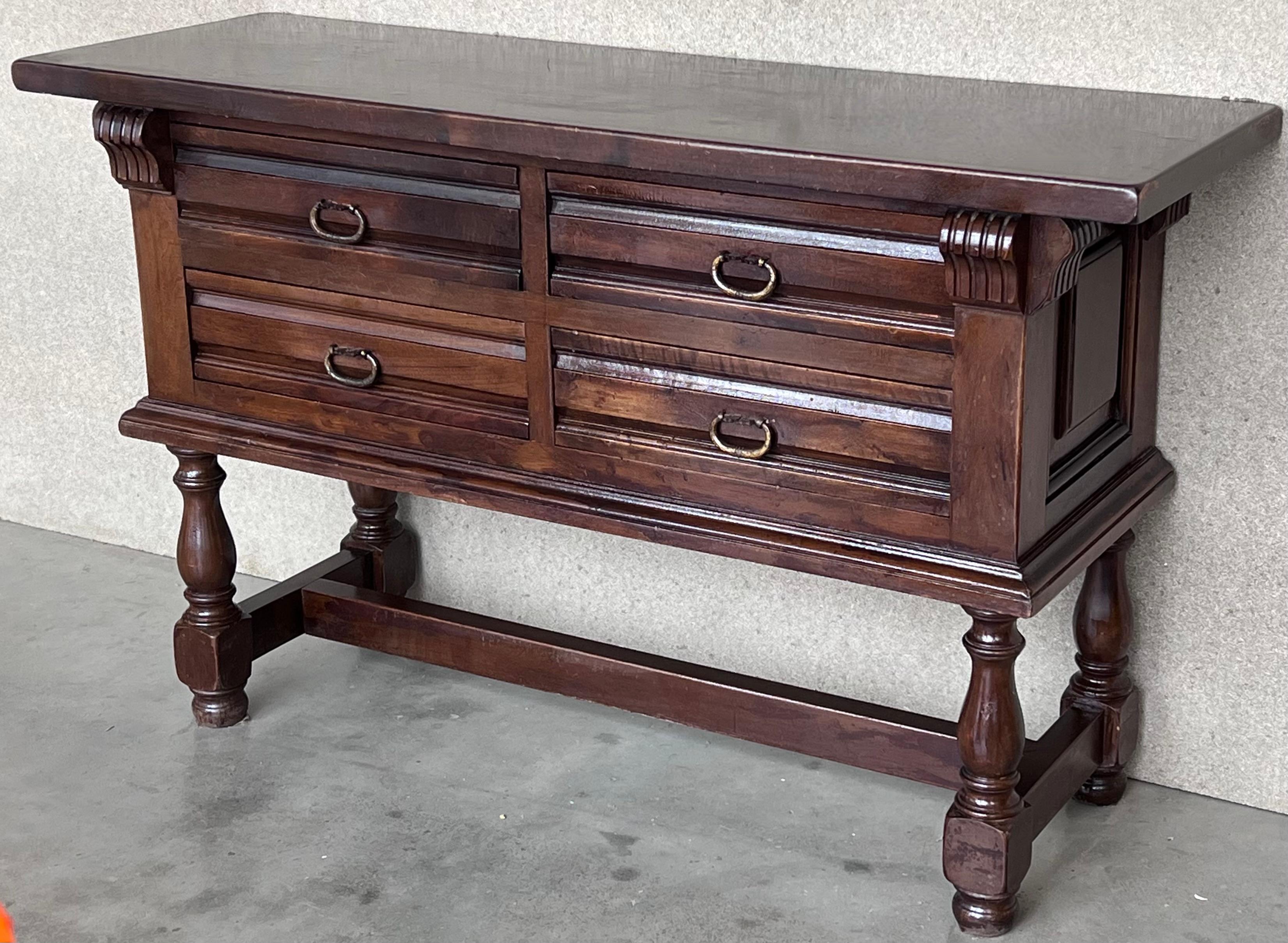 This large Spanish early 20th century features a beautiful one plank rectangular top over four wide carved drawers. Each drawer, featuring slightly different hardware, is adorned with edges and original handmade drop pulls The ensemble shows the
