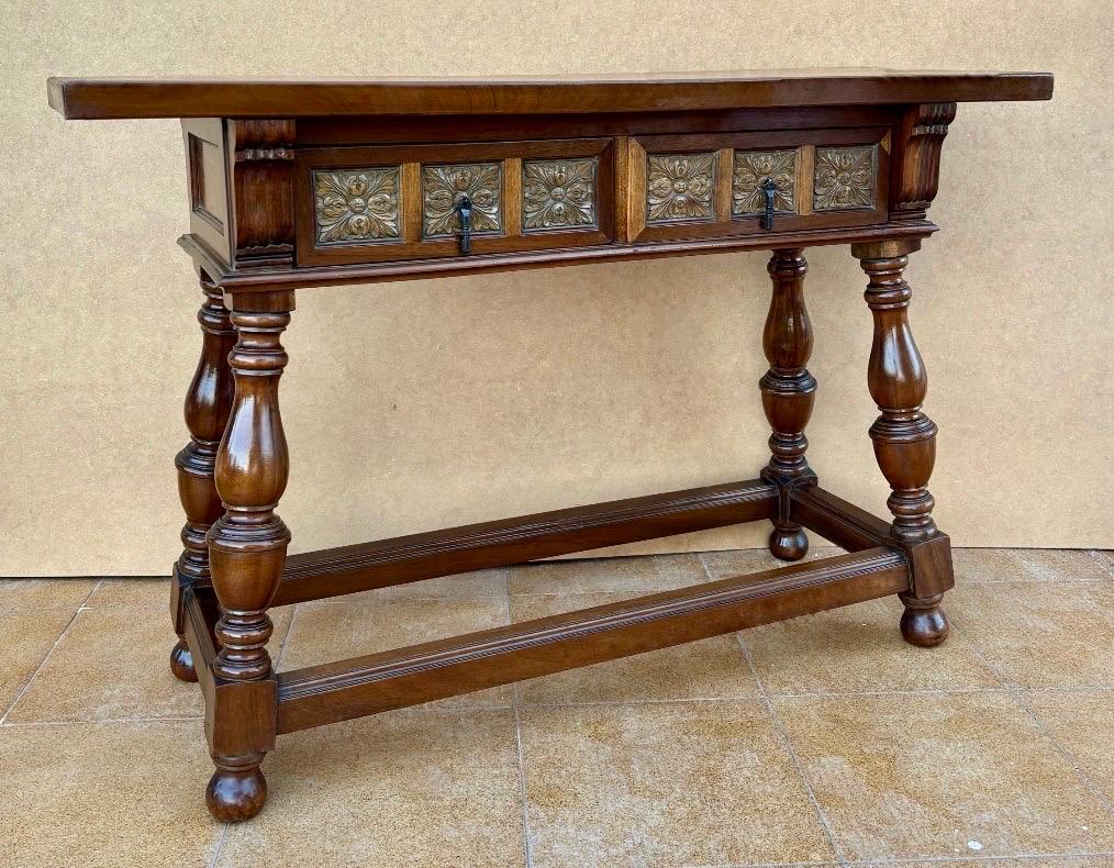 Spanish console table from the early 20th century with 2 drawers and turned legs. Early 20th century carved Spanish console with turned legs and two drawers with hardware. This table with character is of rare narrow depth. It is characteristic of