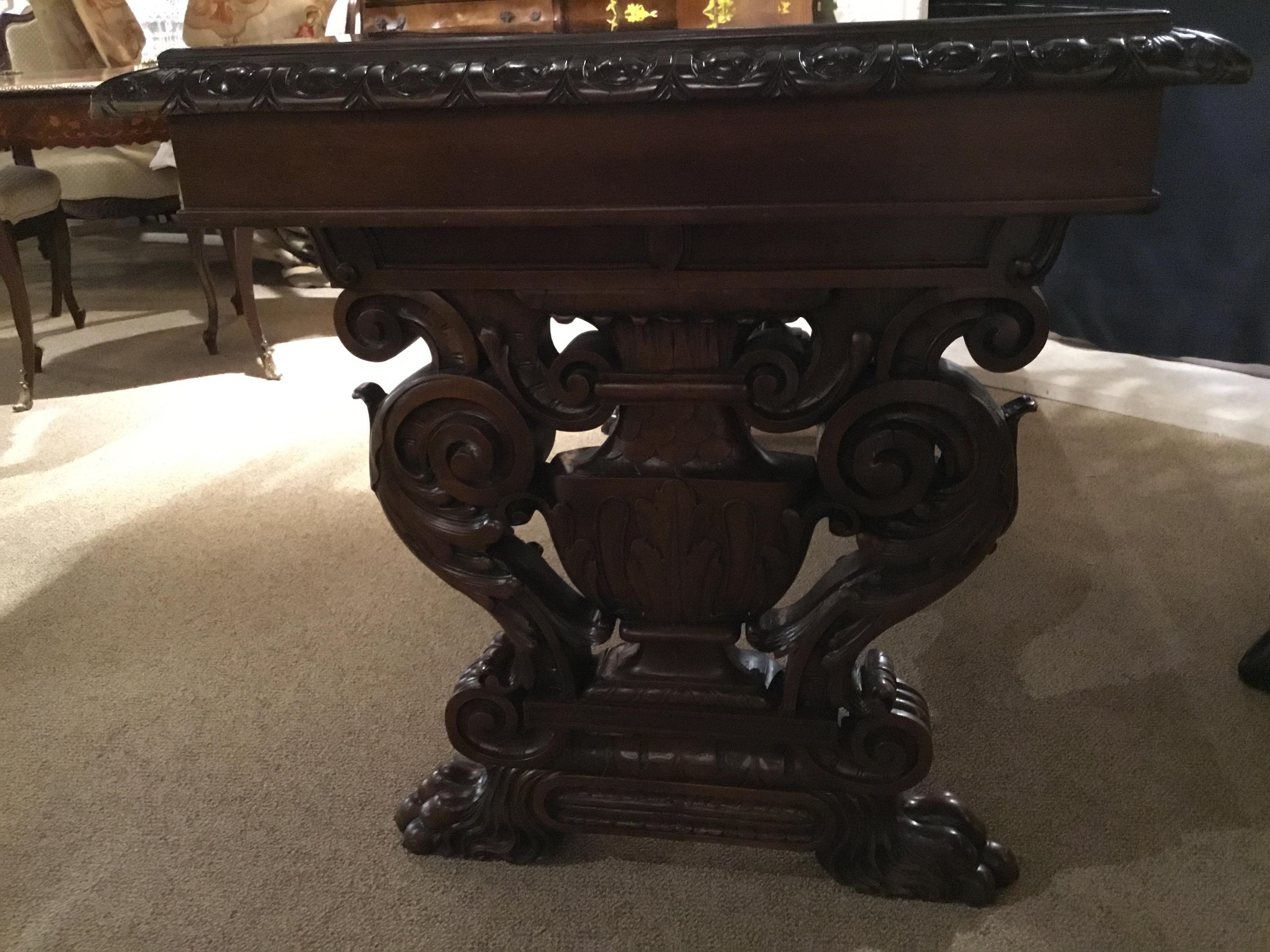 This handsome console has carved ends and scrolling
curved supports on each end. A carved stretcher
runs horizontally between the legs. A gadrooned
edge carving enhances the top edge and the top has
a bronze mirror. Dark walnut finish is in very