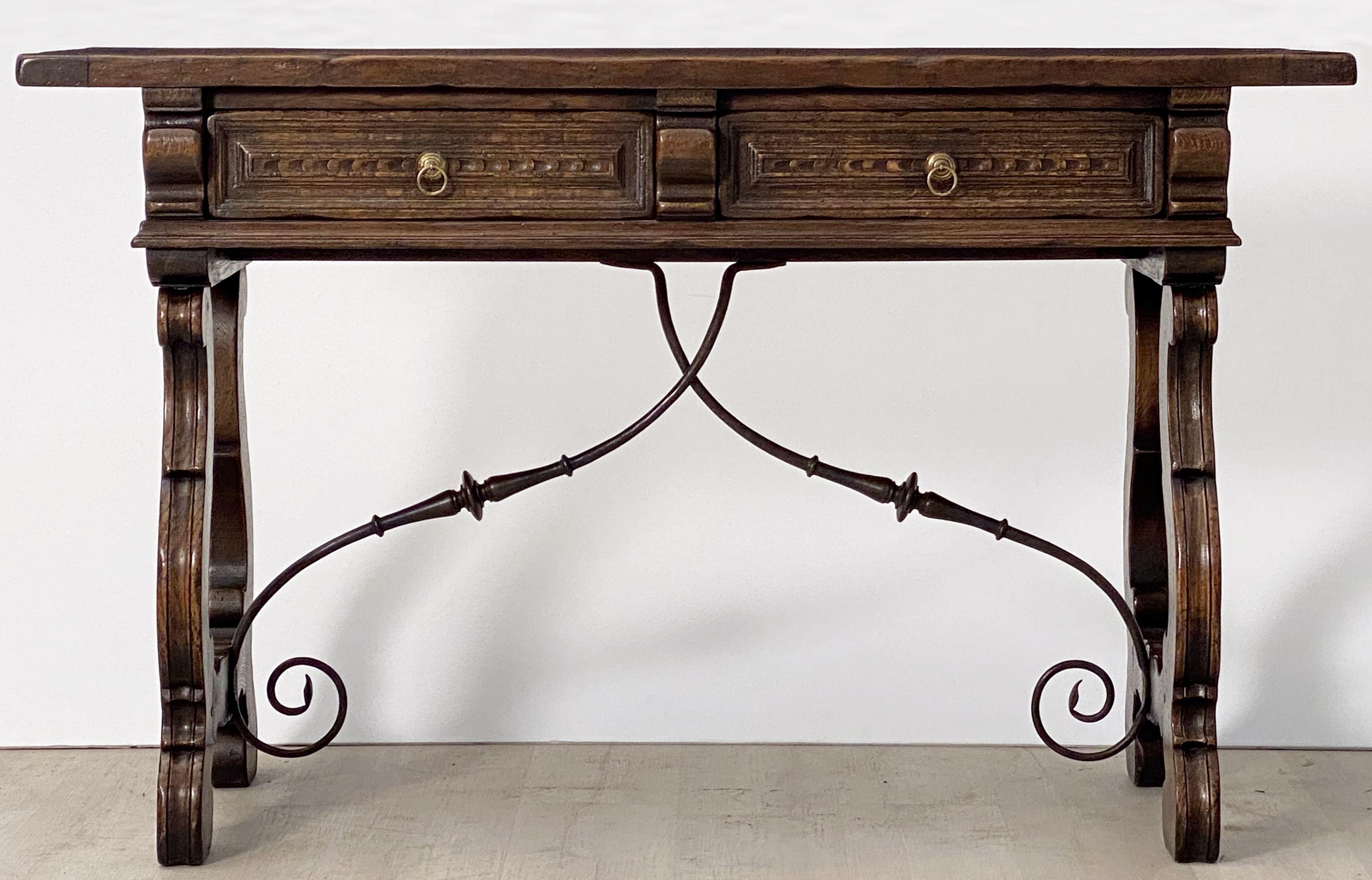A handsome Spanish console table or buffet server of oak featuring a rectangular plank top over a frieze of two drawers, with brass pulls, and standing on turned wood supports with wrought ironwork braces in a cross-bar design.
