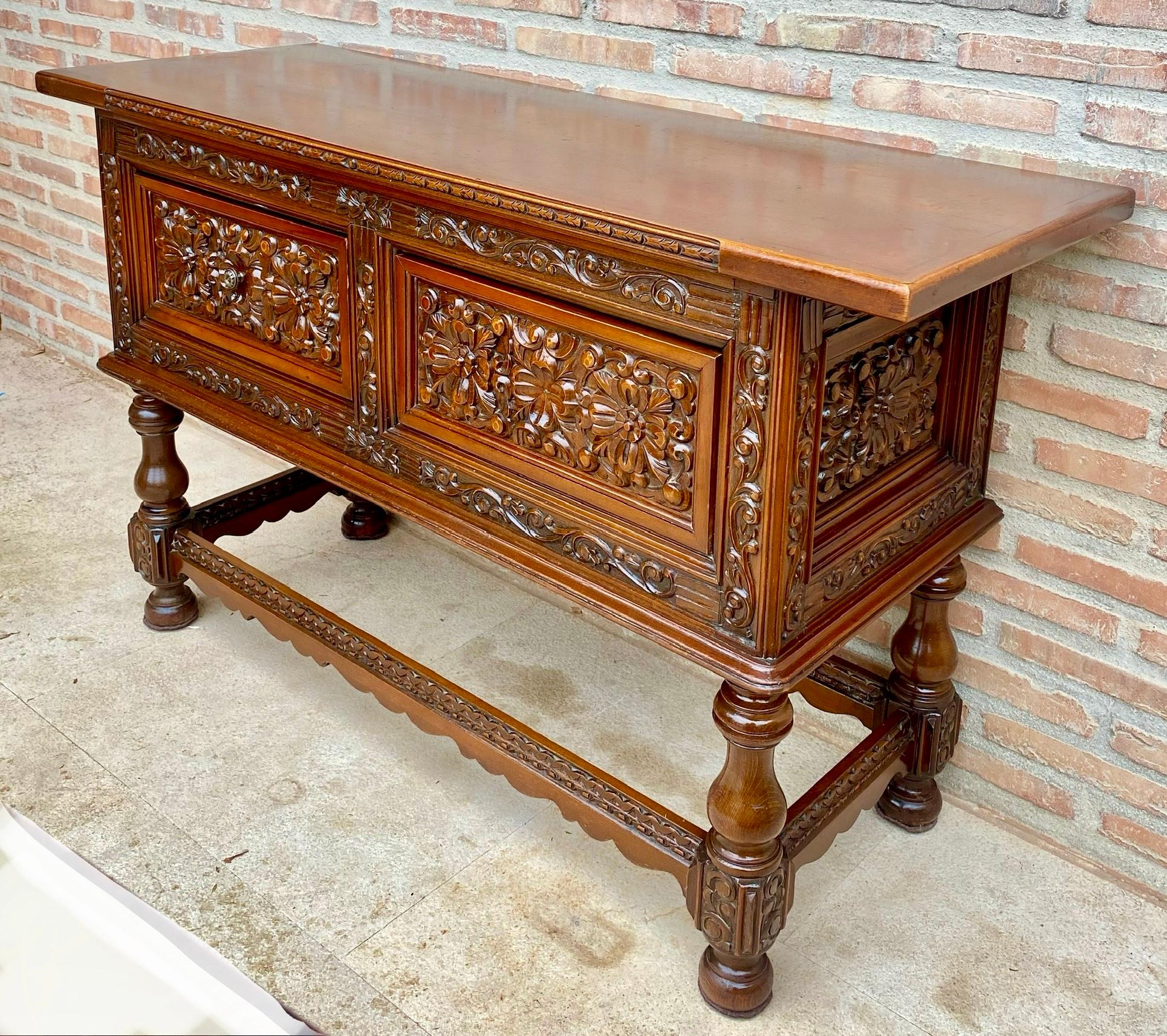 This large Spanish piece of furniture from the early 20th century features a beautiful rectangular one-slat countertop on four large carved drawers. Each drawer, with slightly different hardware, is adorned with floral motifs and each drawer with