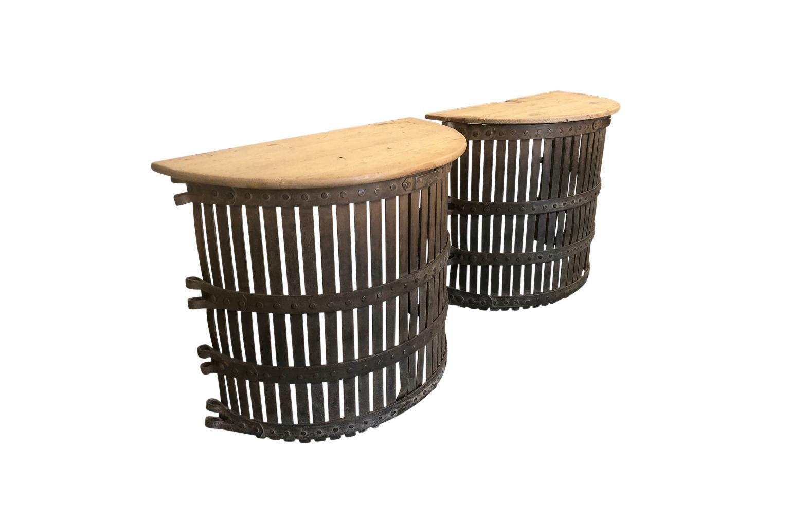 A very charming pair of Spanish demilune console tables. These console tables are composed from forged iron tree guards with naturally washed wooded tops. A fun accent for any casual environment.